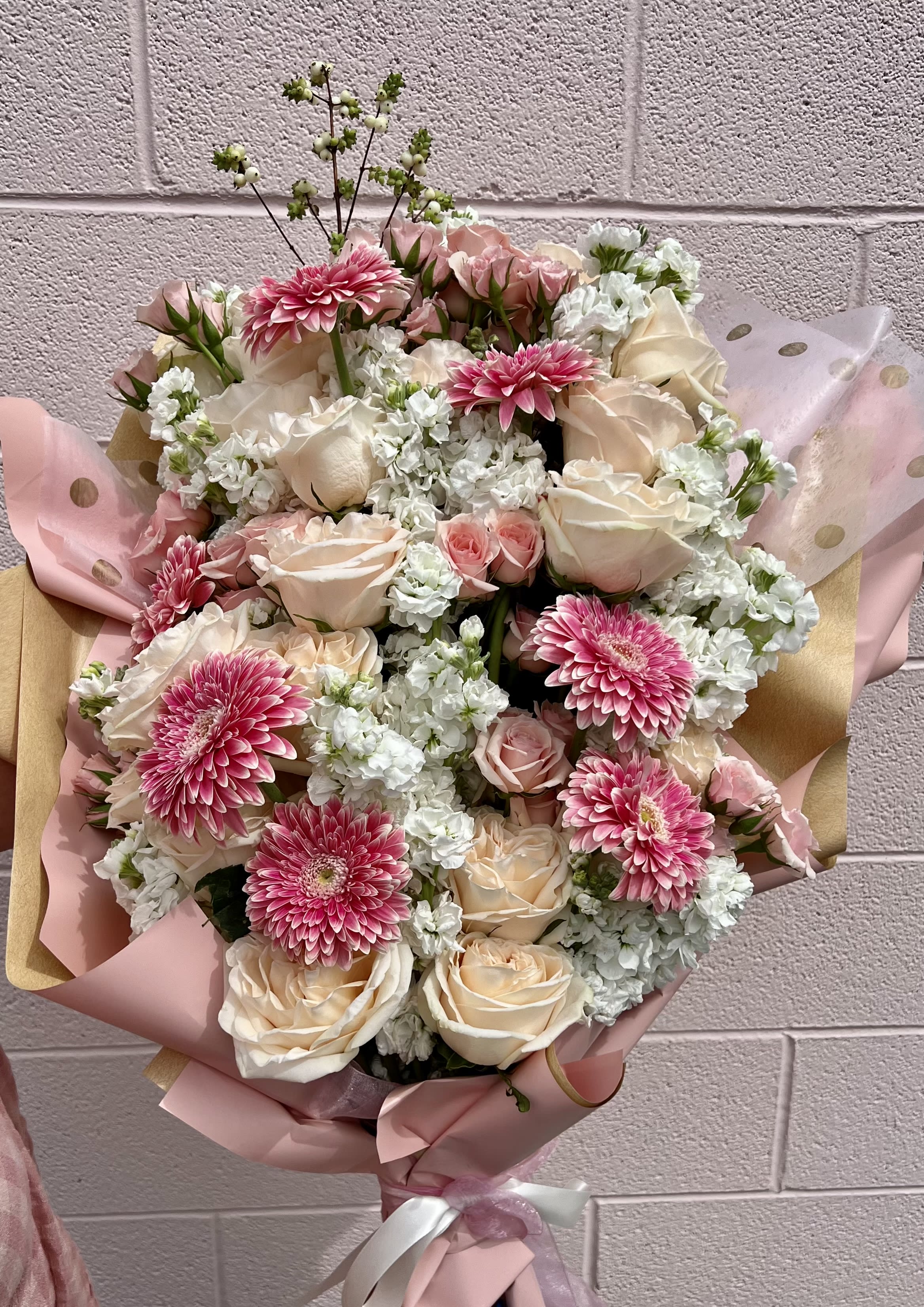 Bouquet of pink gerbera daisies and cream roses wrapped in pink paper