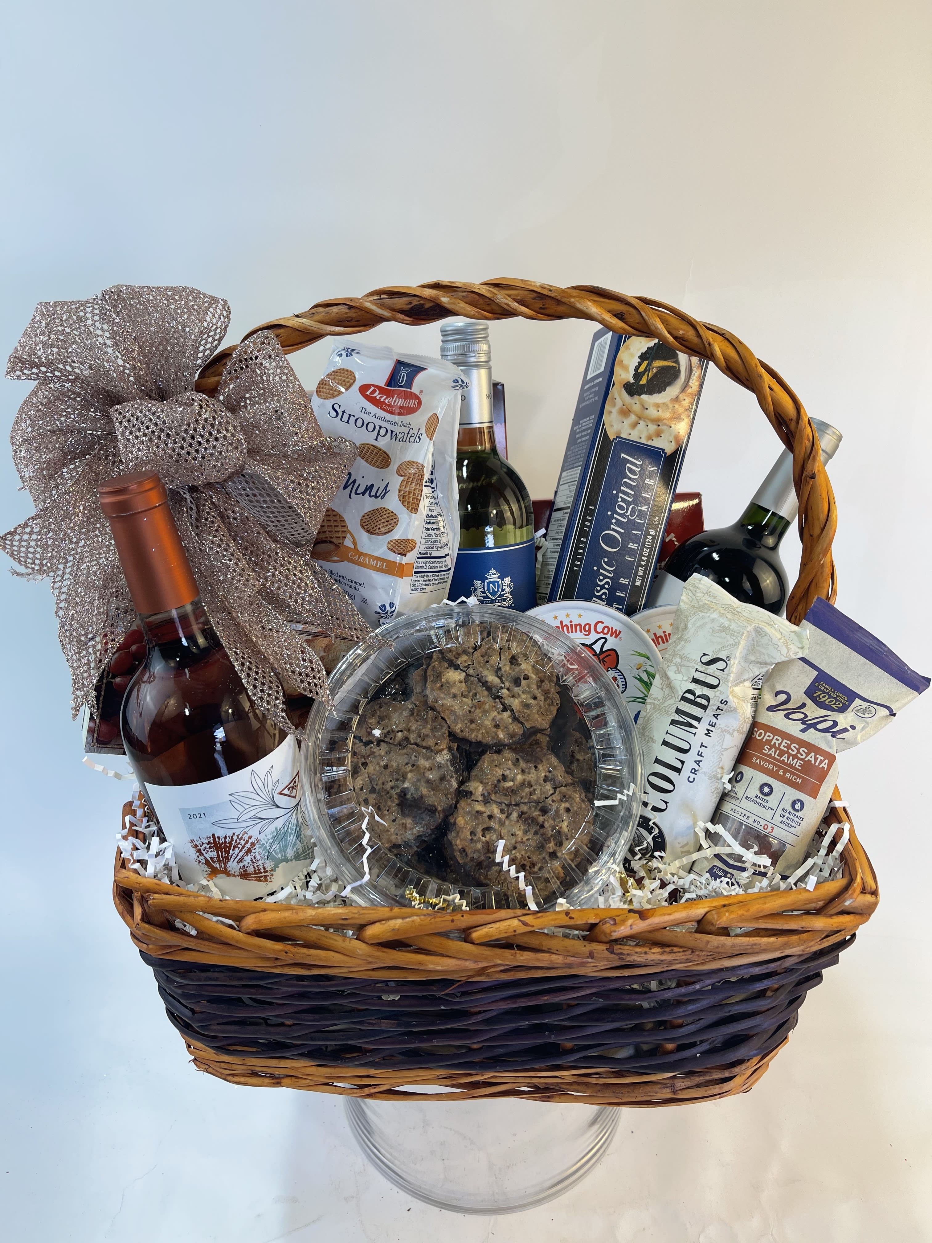 Gift basket with wine, snacks, and cookies in a wicker basket