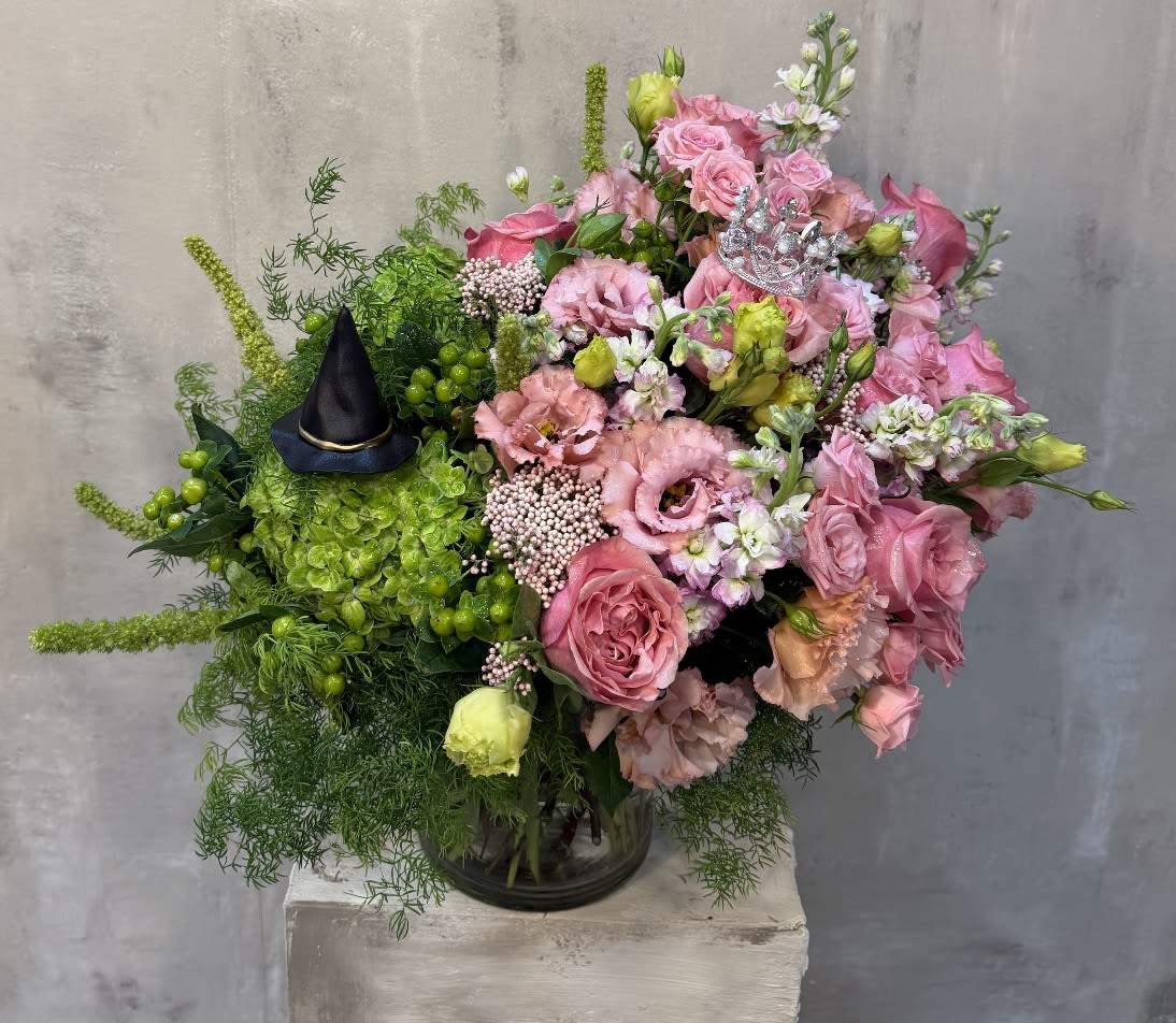Pink rose bouquet with green accents and a small black witch hat