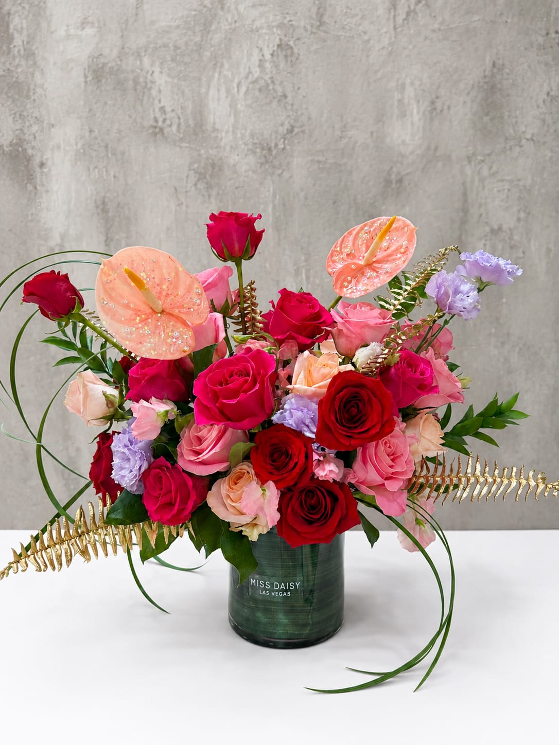 Mixed roses and anthuriums in a green vase