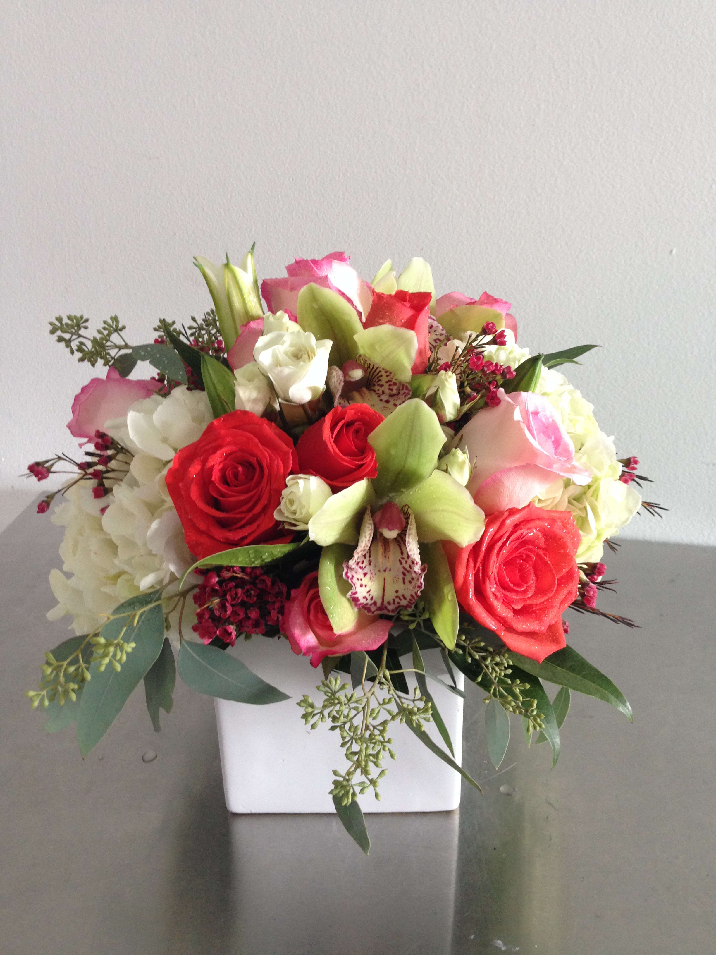 Mixed bouquet of red and pink roses with white blooms in a white vase