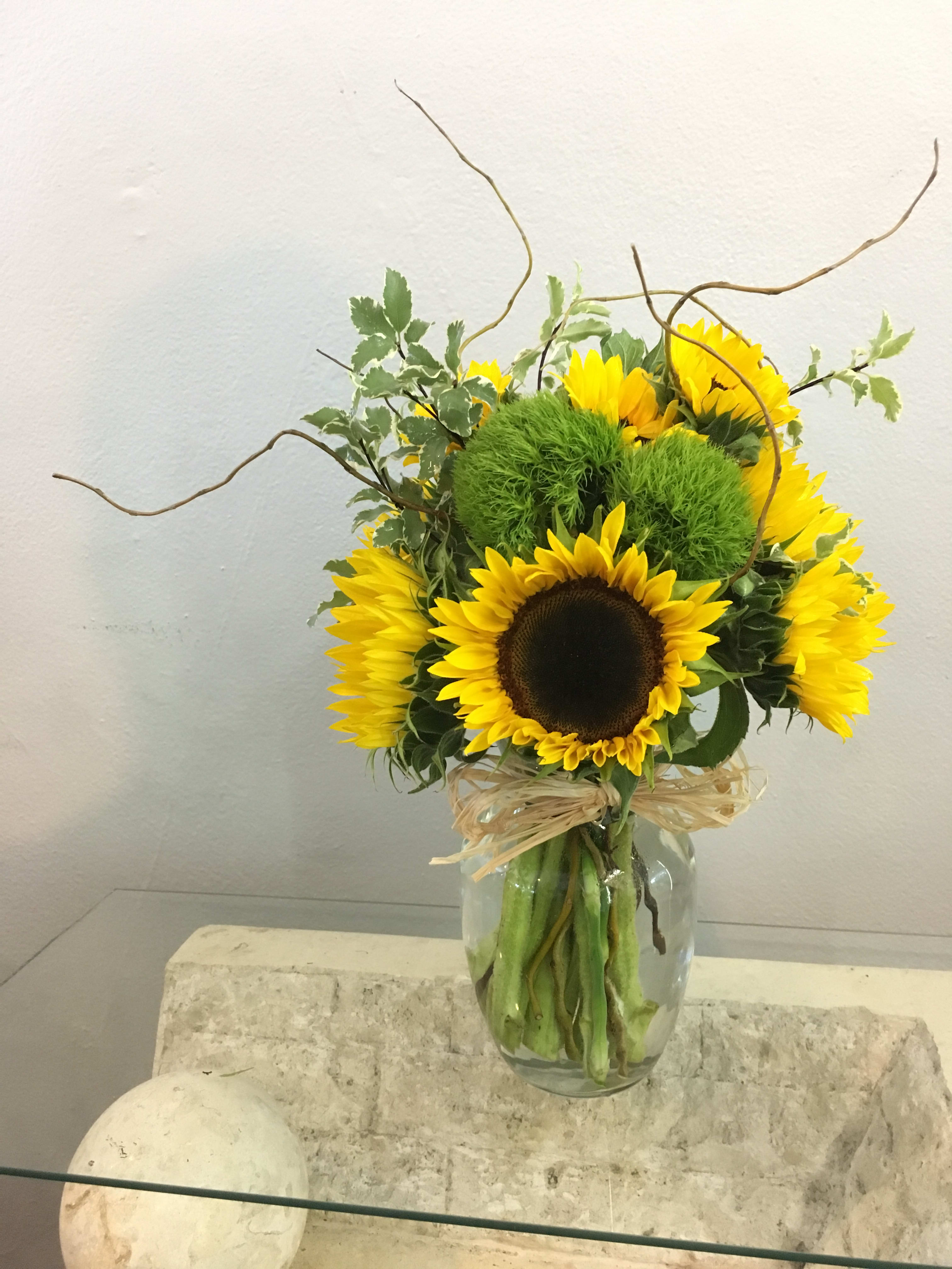 Sunflower arrangement in a glass vase with curly branches