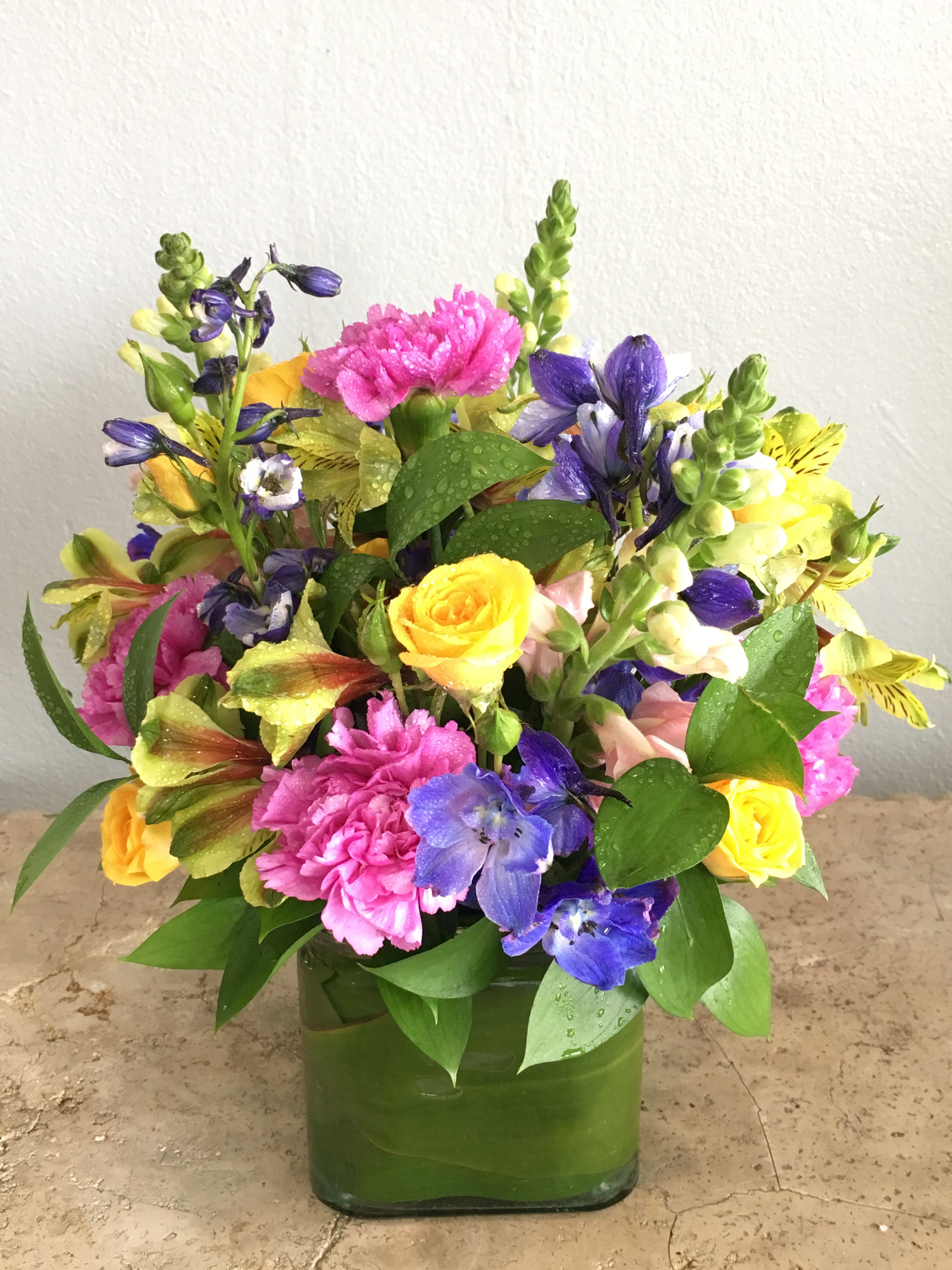 Colorful bouquet of mixed flowers in a green glass vase