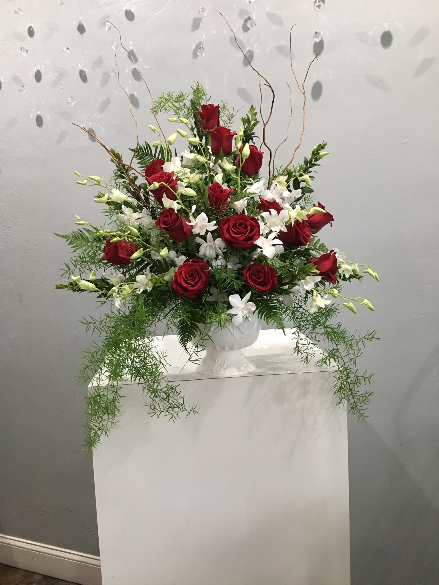Red roses and white flowers arranged in a white vase