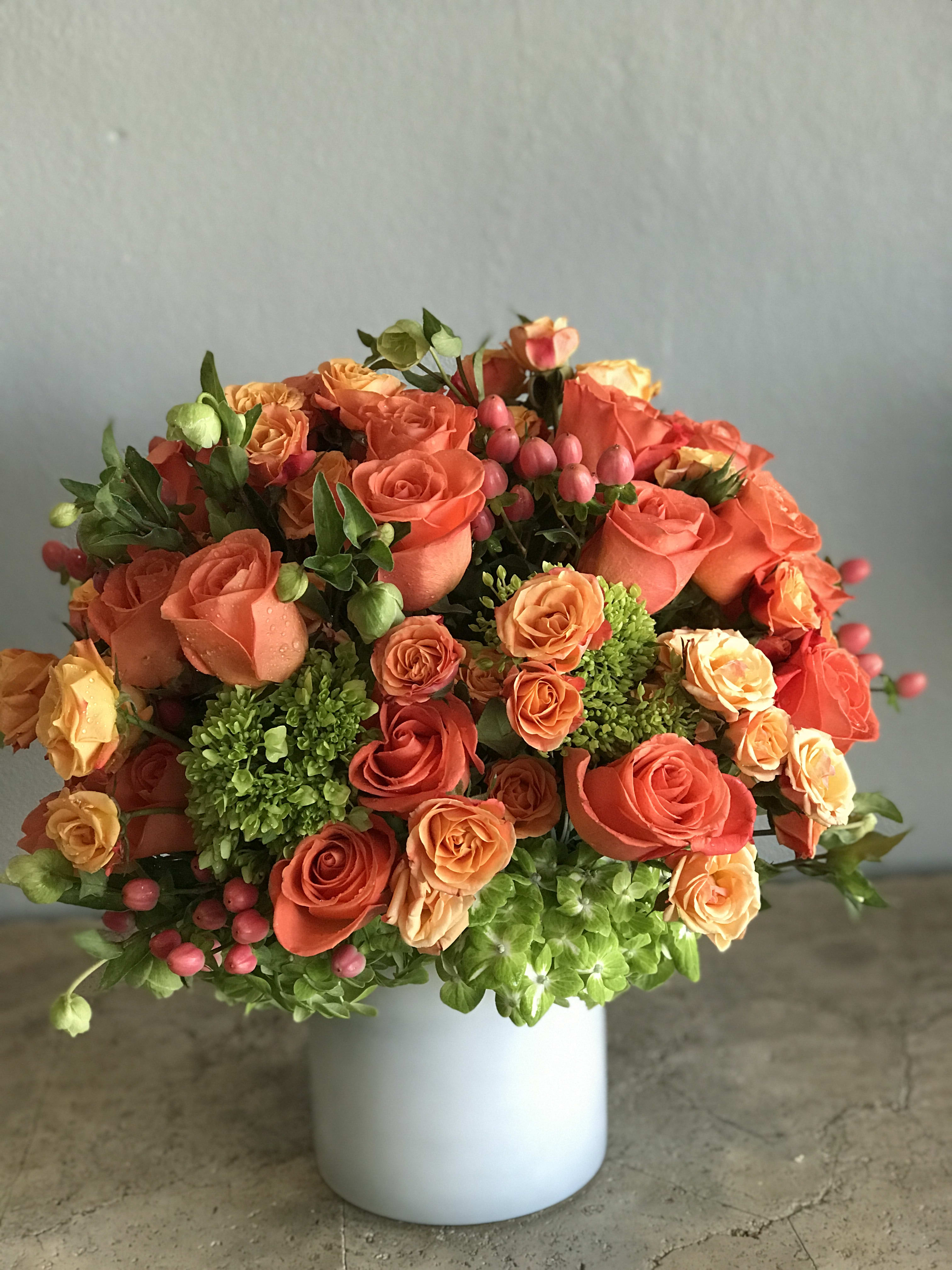 Orange and peach rose bouquet in a white vase