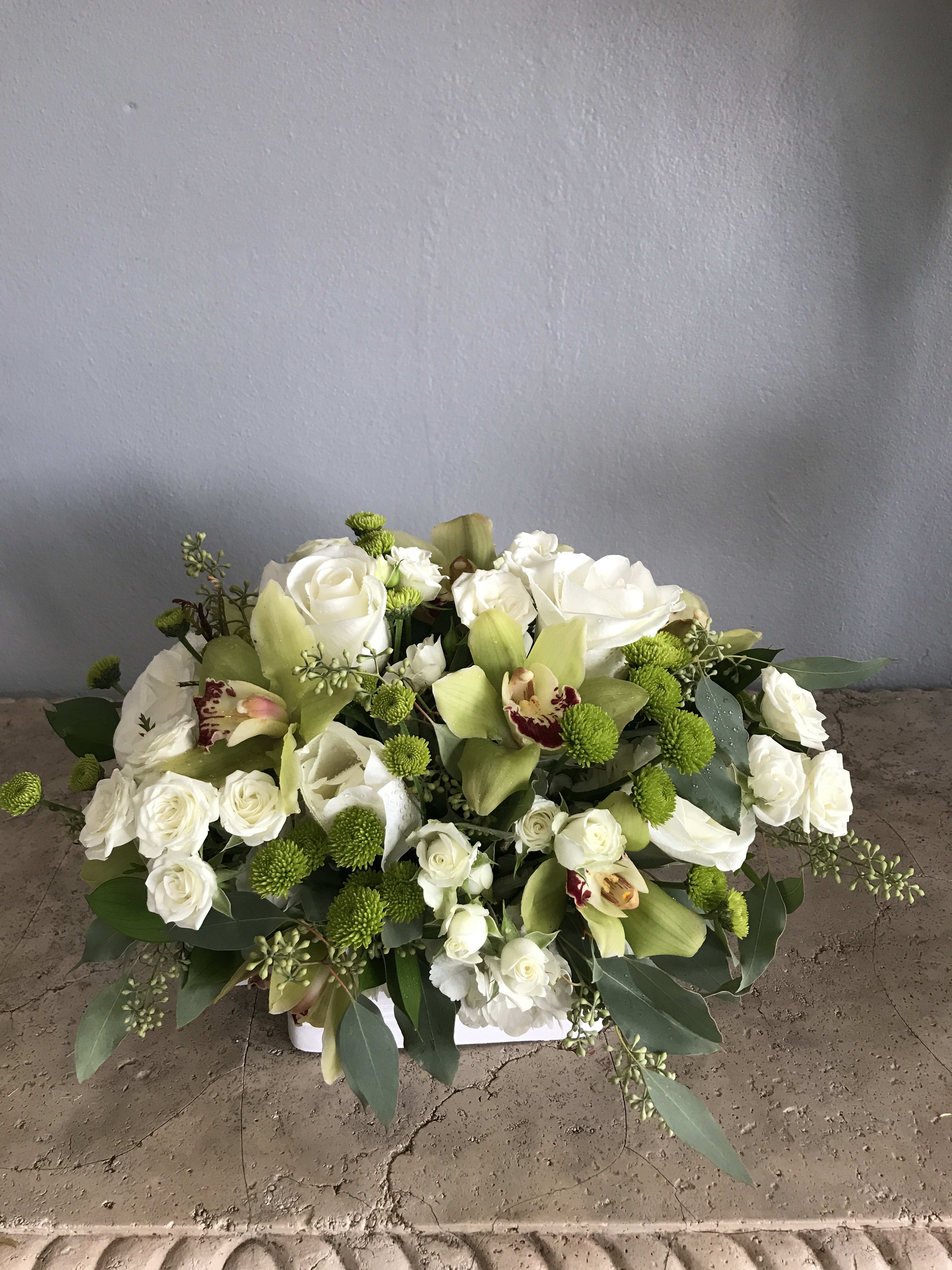 White roses and green orchids in a low floral arrangement
