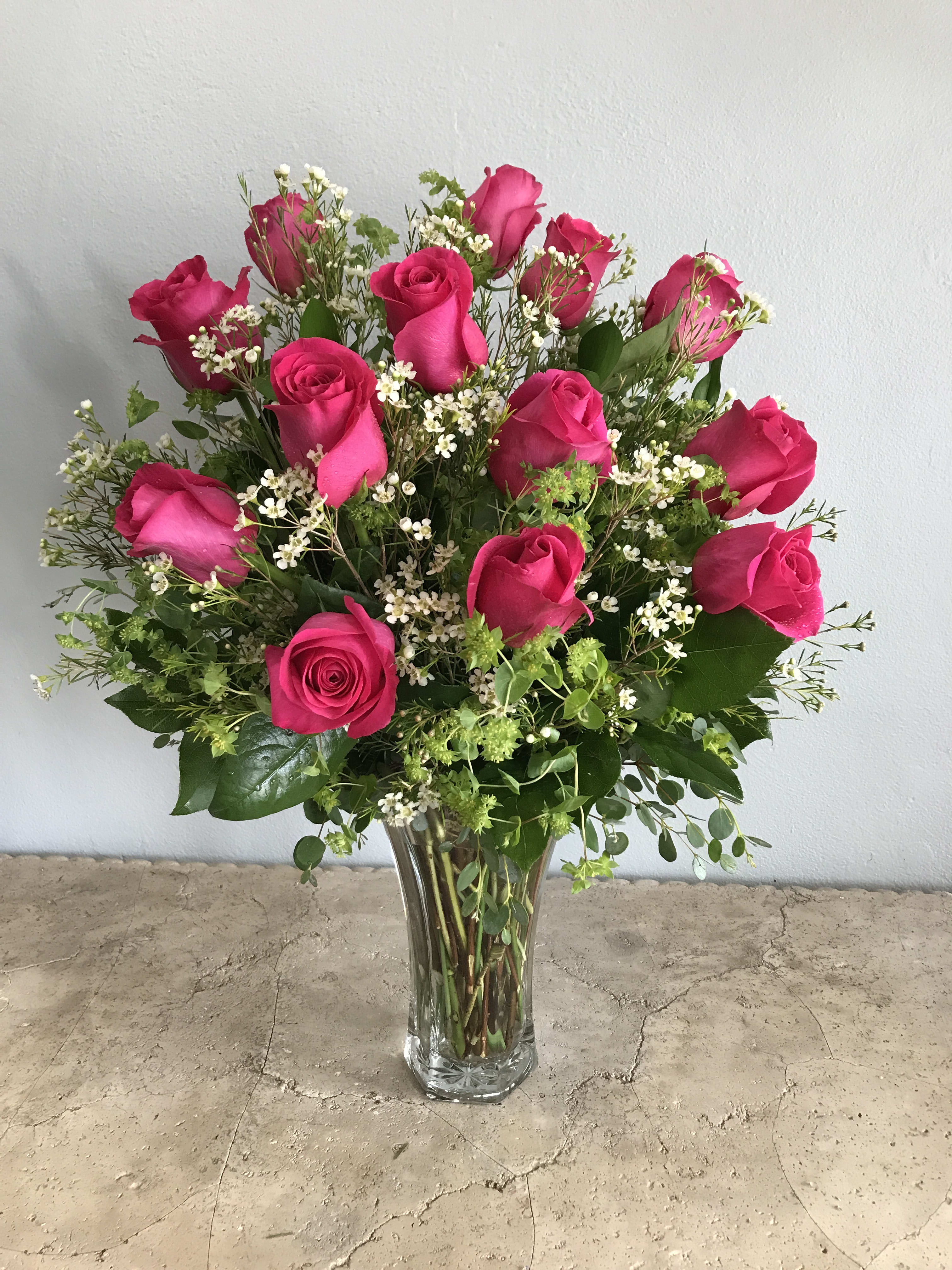 Pink roses arranged in a clear glass vase with small white filler flowers