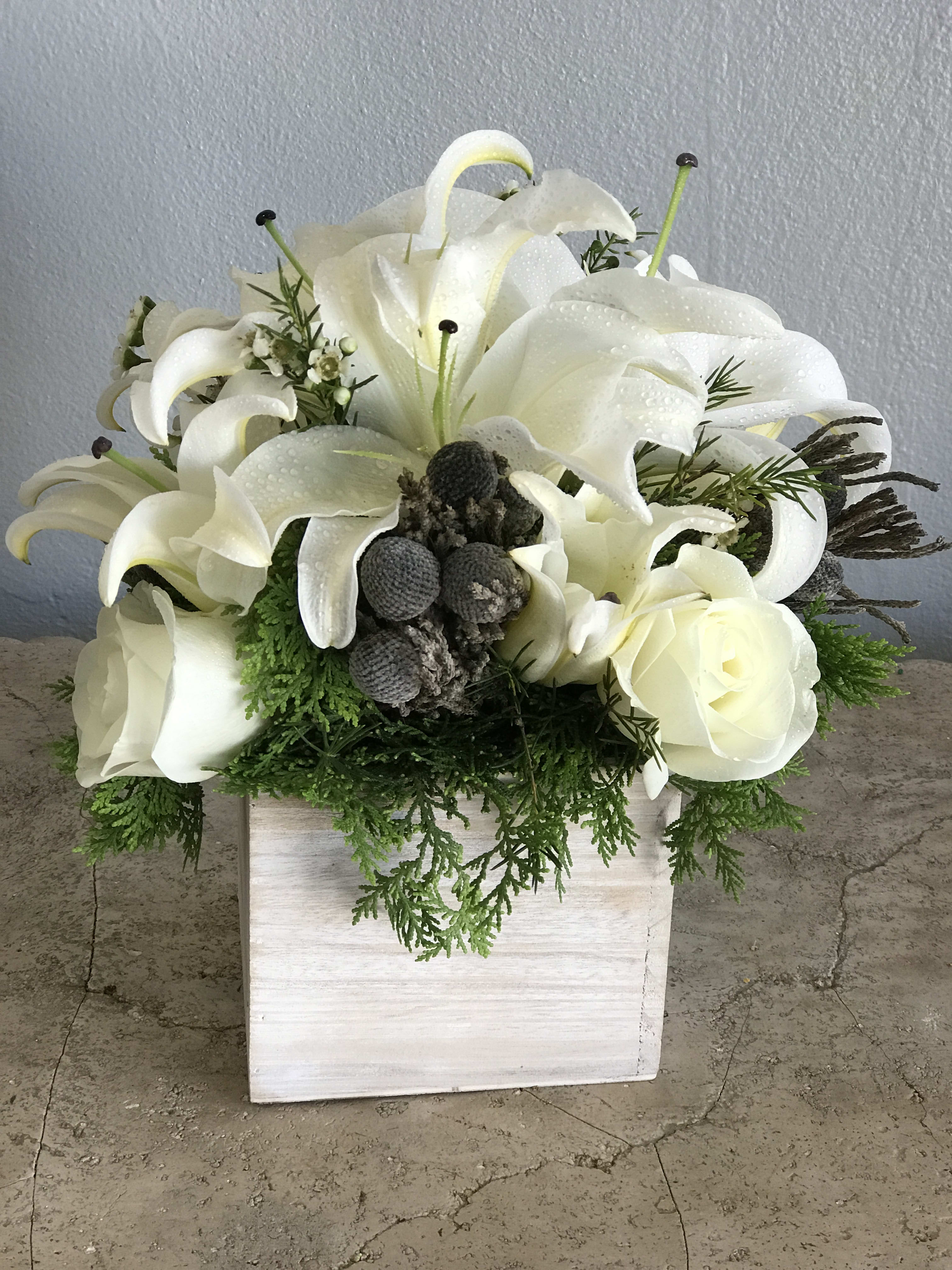 White calla lilies and roses arranged in a white wooden box
