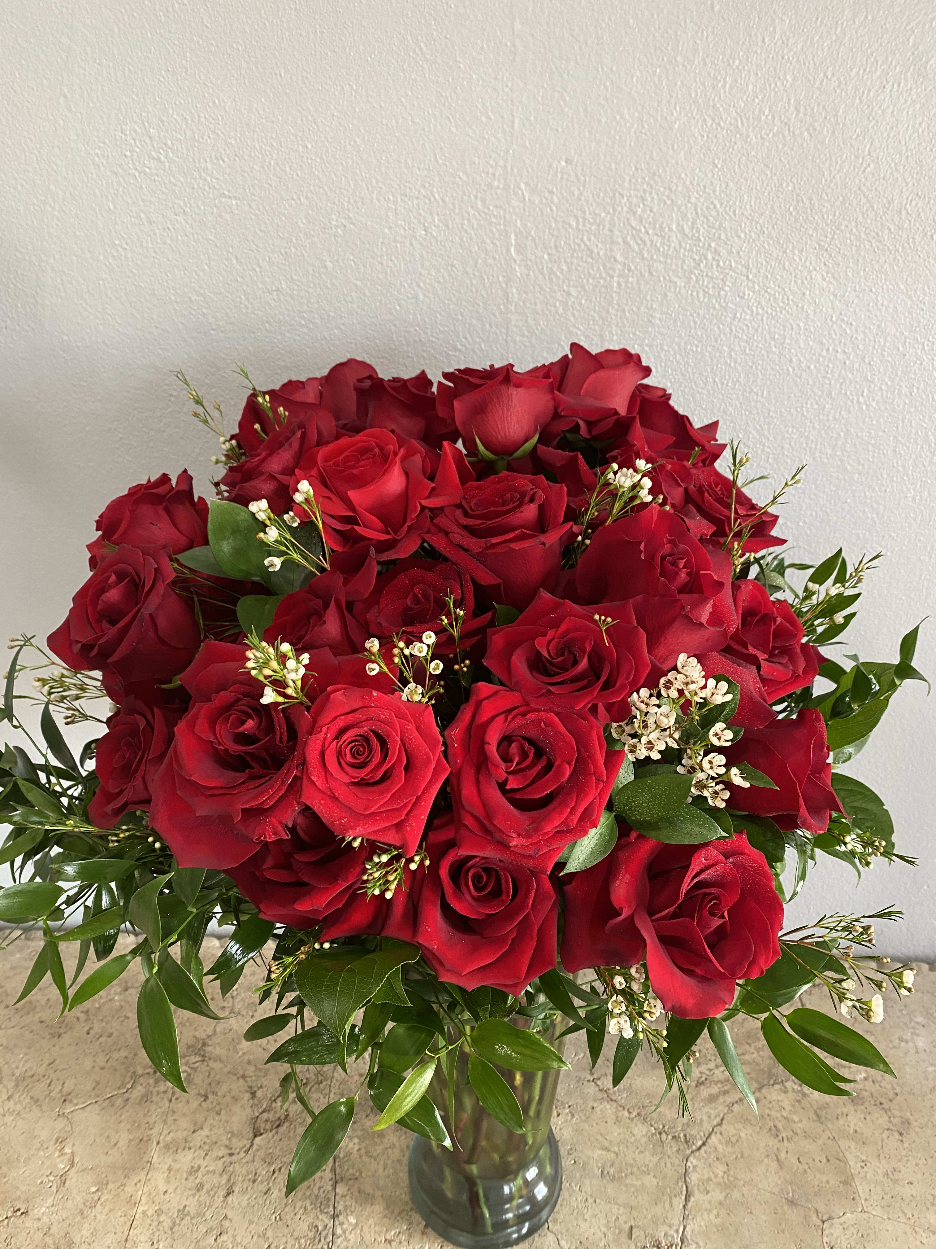 Bouquet of red roses in a glass vase with greenery