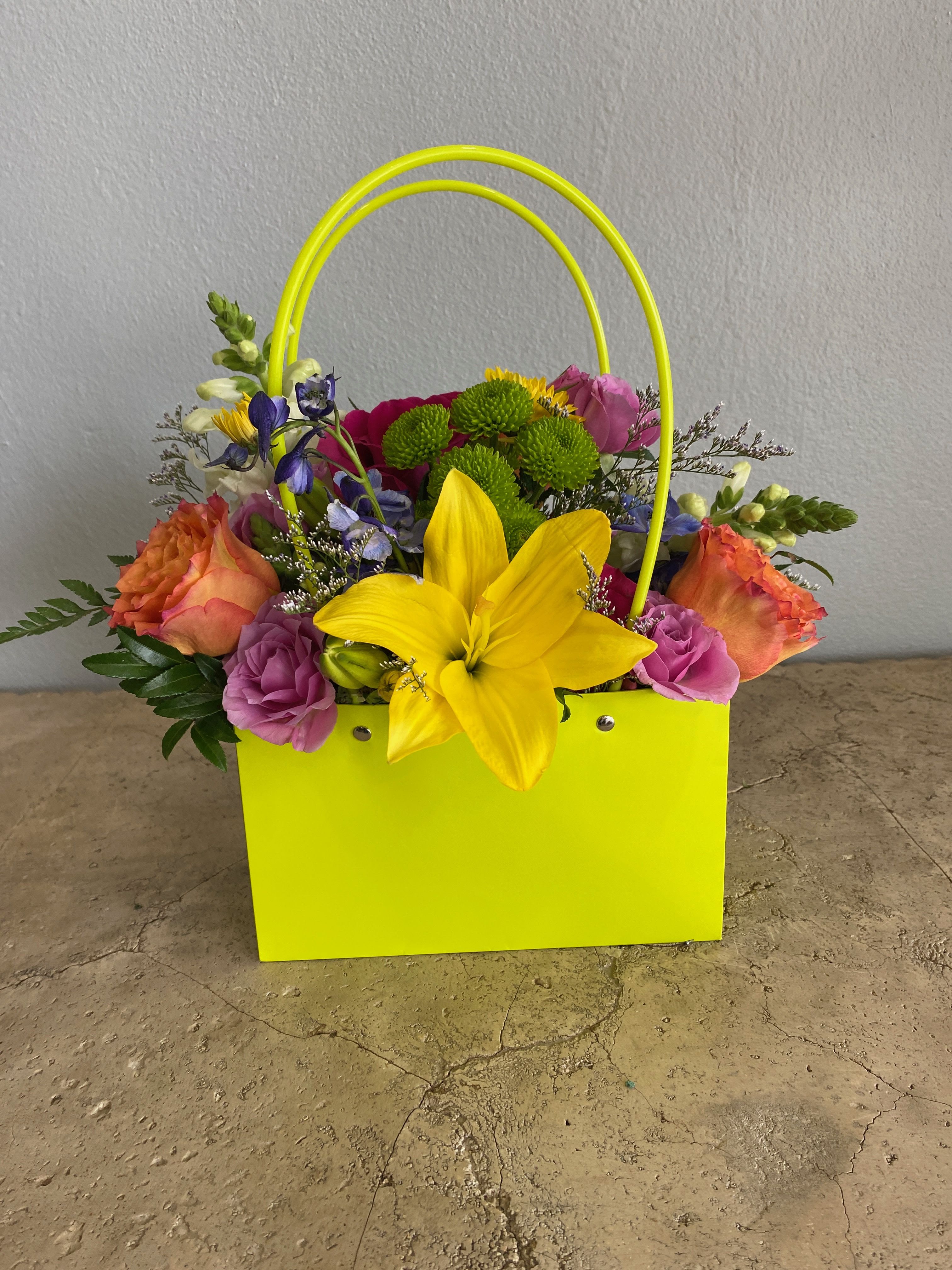 Bright mixed flower arrangement in a neon yellow gift bag