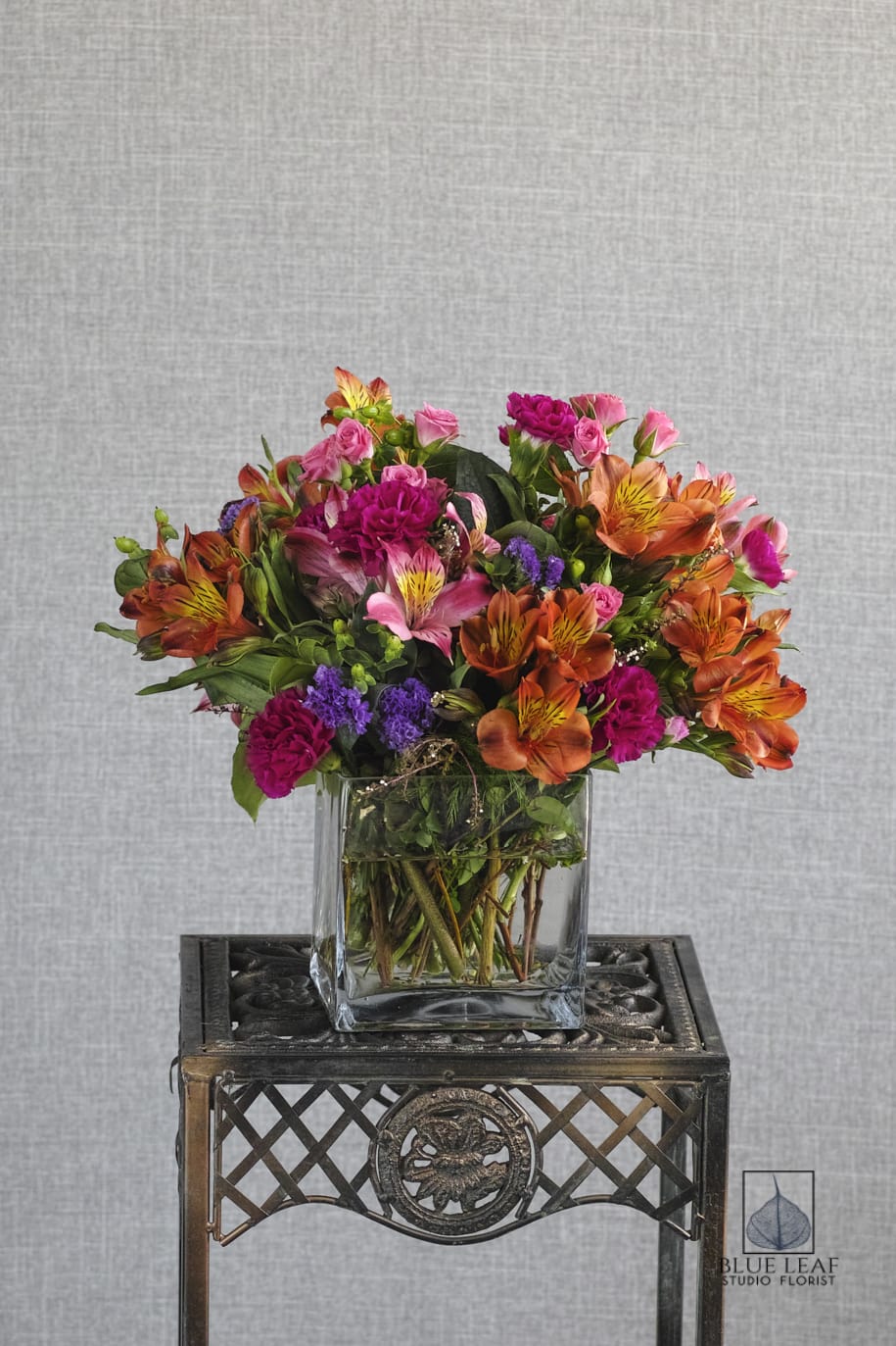 Colorful bouquet of orange, pink, and purple flowers in a clear glass vase