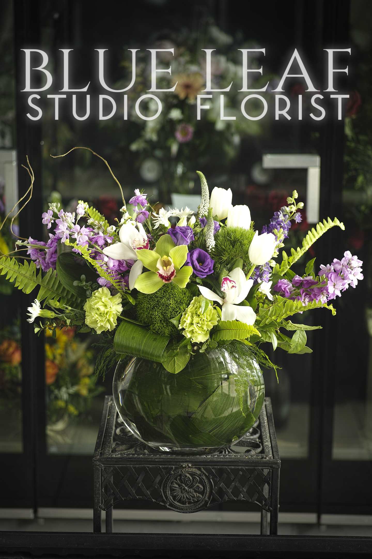 Purple and white floral arrangement in a round glass vase