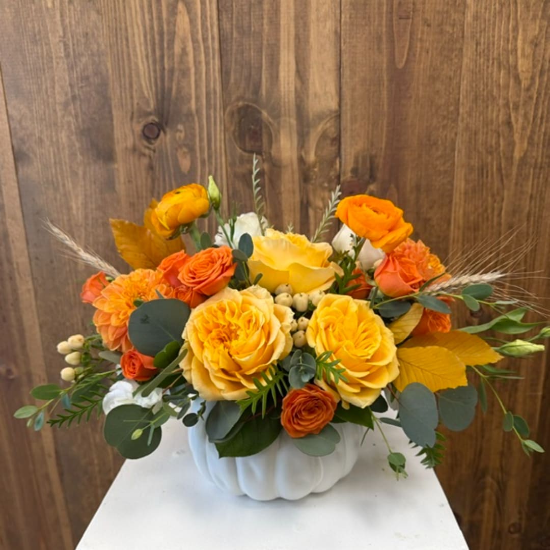 Yellow and orange rose arrangement in a white pumpkin vase