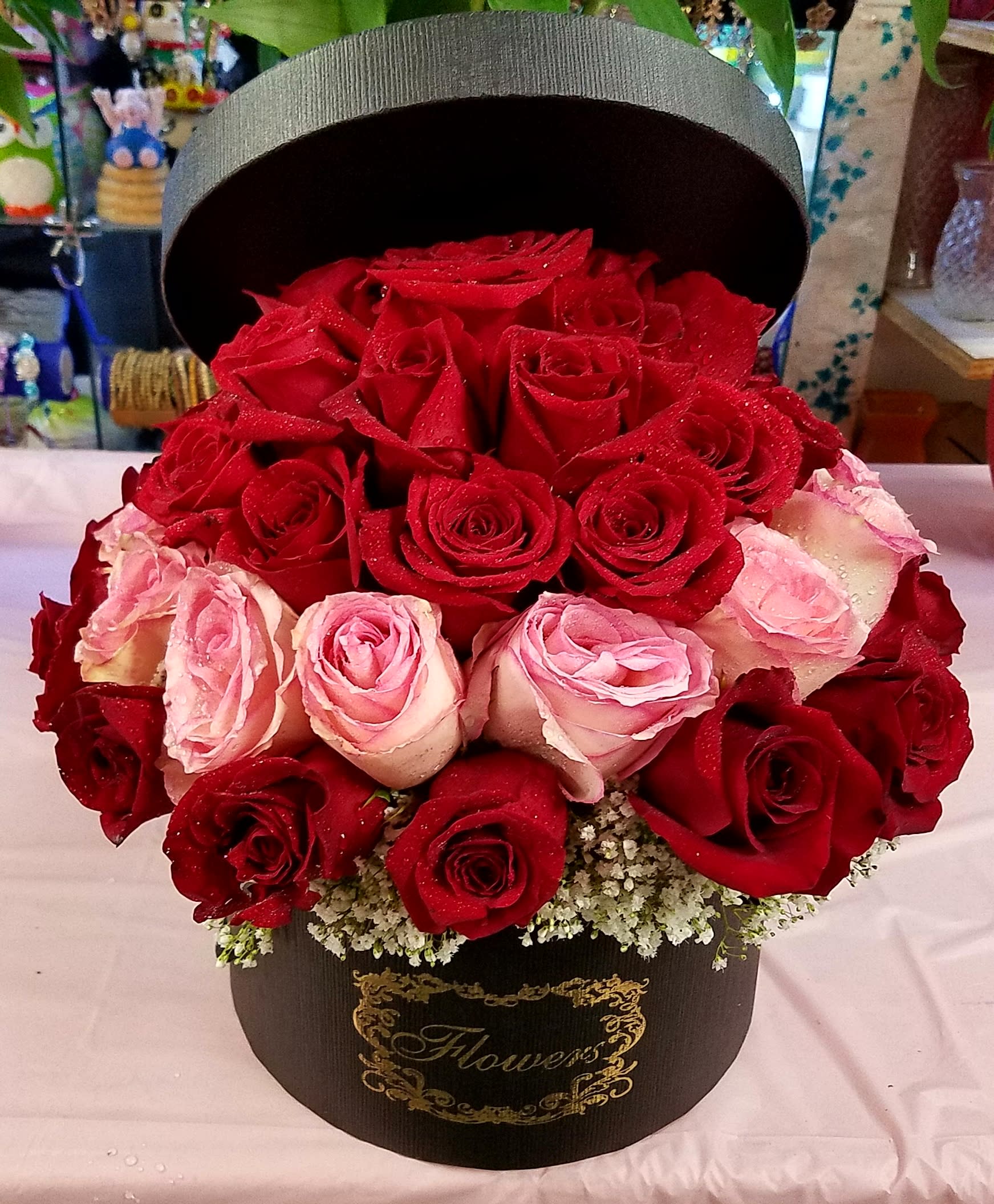 Red and pink roses arranged in a black hatbox