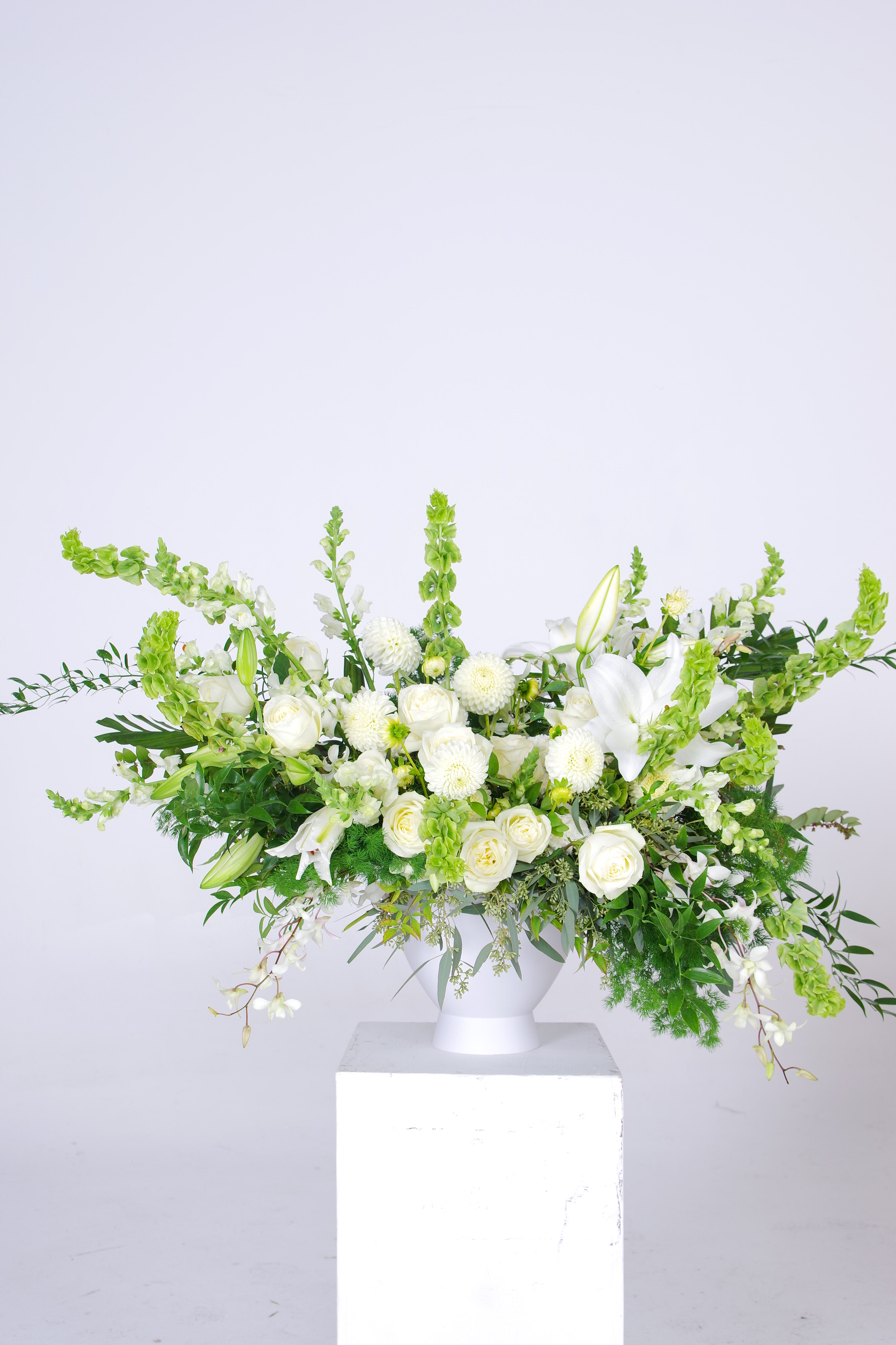 White floral arrangement in a white pedestal vase