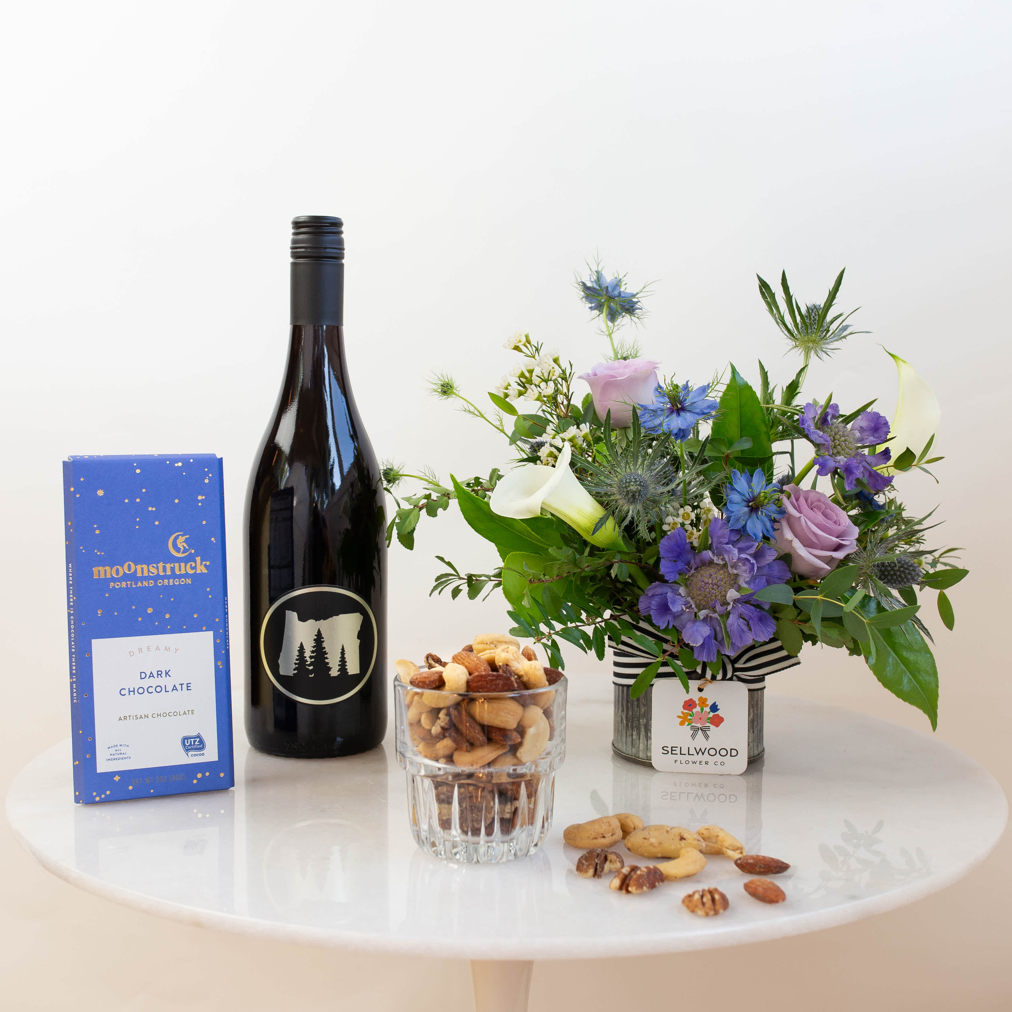 Flower arrangement with wine, chocolates, and nuts on a table
