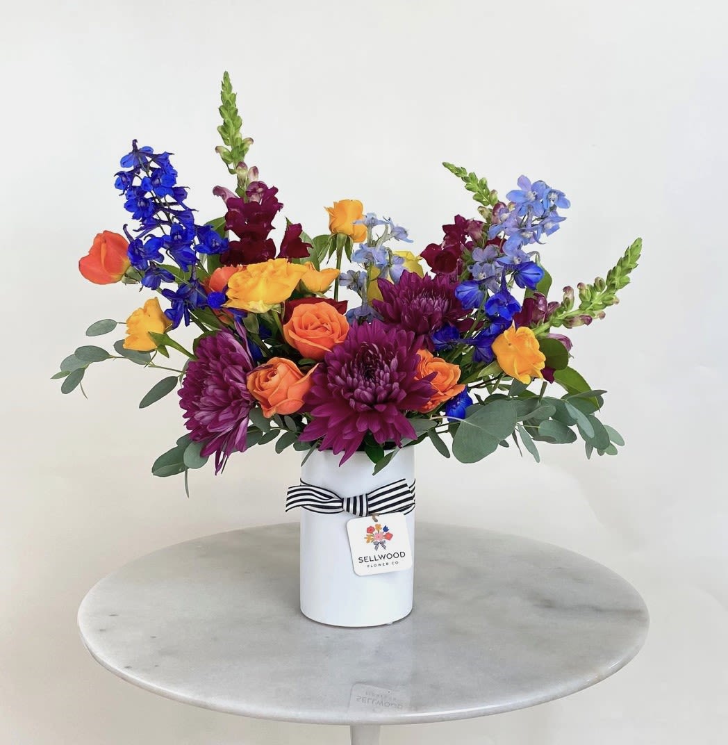 Colorful mixed bouquet in a white vase with a striped ribbon