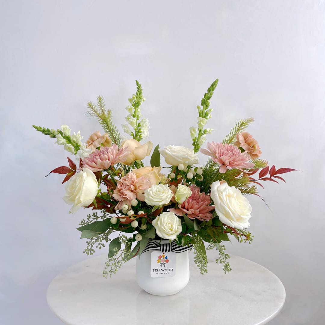 Pink and white mixed bouquet in a white vase with a striped ribbon