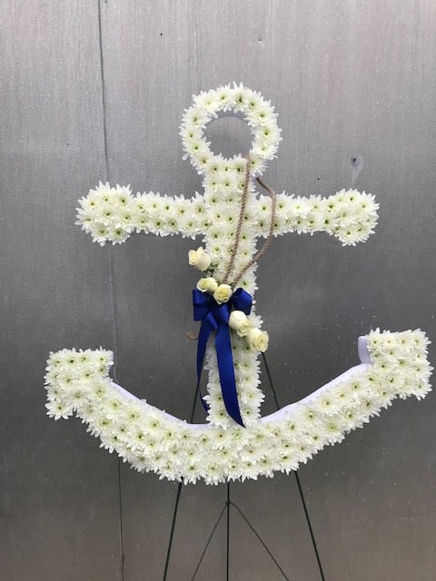 Anchor-shaped standing spray of white flowers with blue ribbon and rope accent.