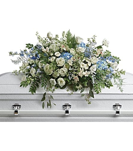White and blue floral casket spray on a white coffin