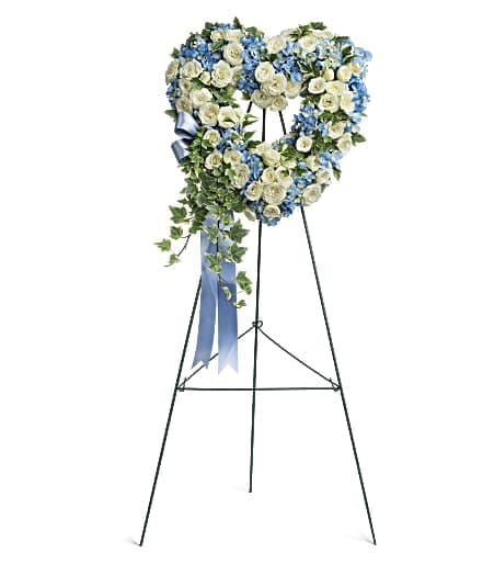 Heart-shaped floral wreath on a standing easel with blue and white flowers
