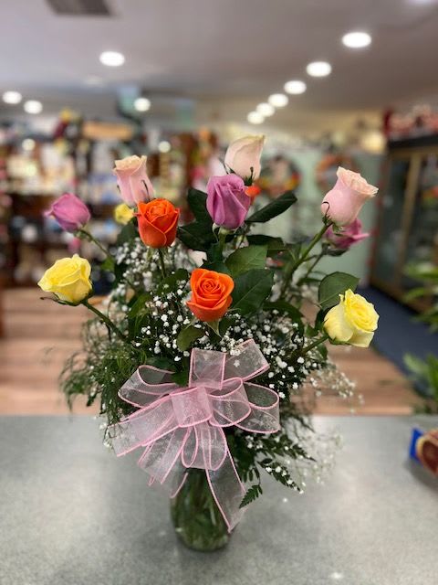 Mixed roses in a glass vase with a pink ribbon bow
