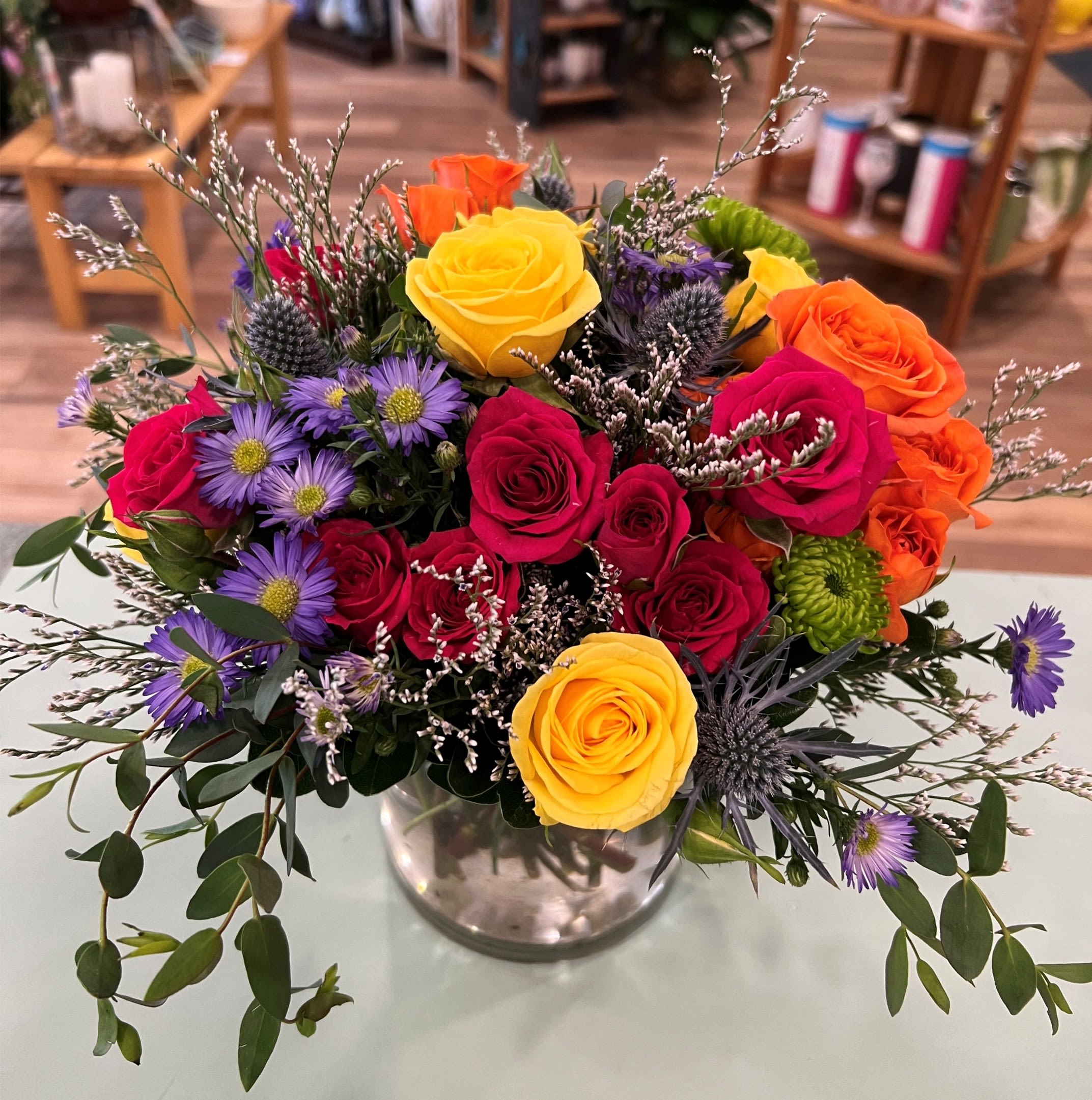 Bright Wishes (BW) - Our 5 in cylinder vase is filled with assorted colored spray roses, green buttons, thistle and accent flowers. Perfect size for a desk or end table.  ***Colors may vary based on availability.
