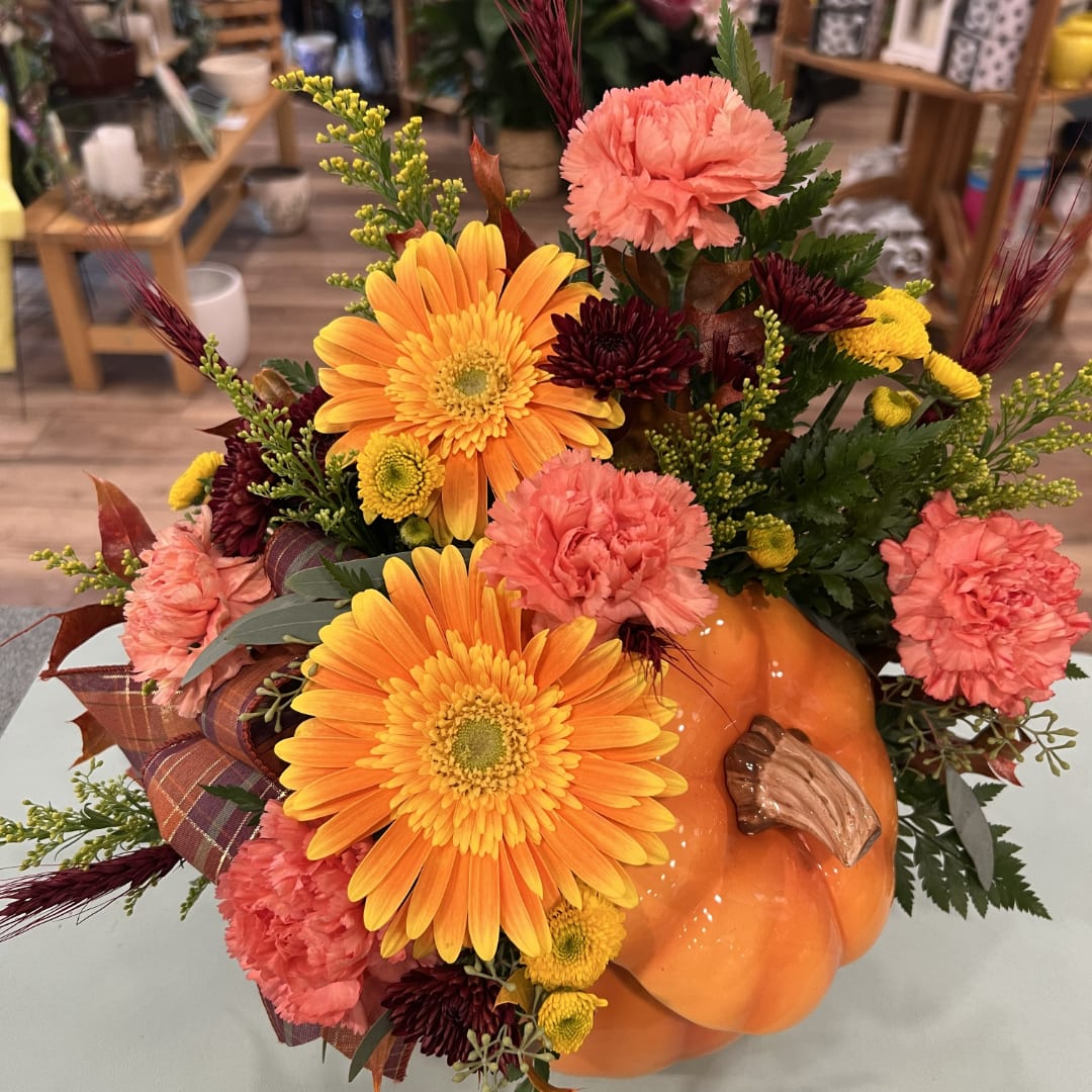 Autumn floral arrangement in a pumpkin container with orange and pink blooms
