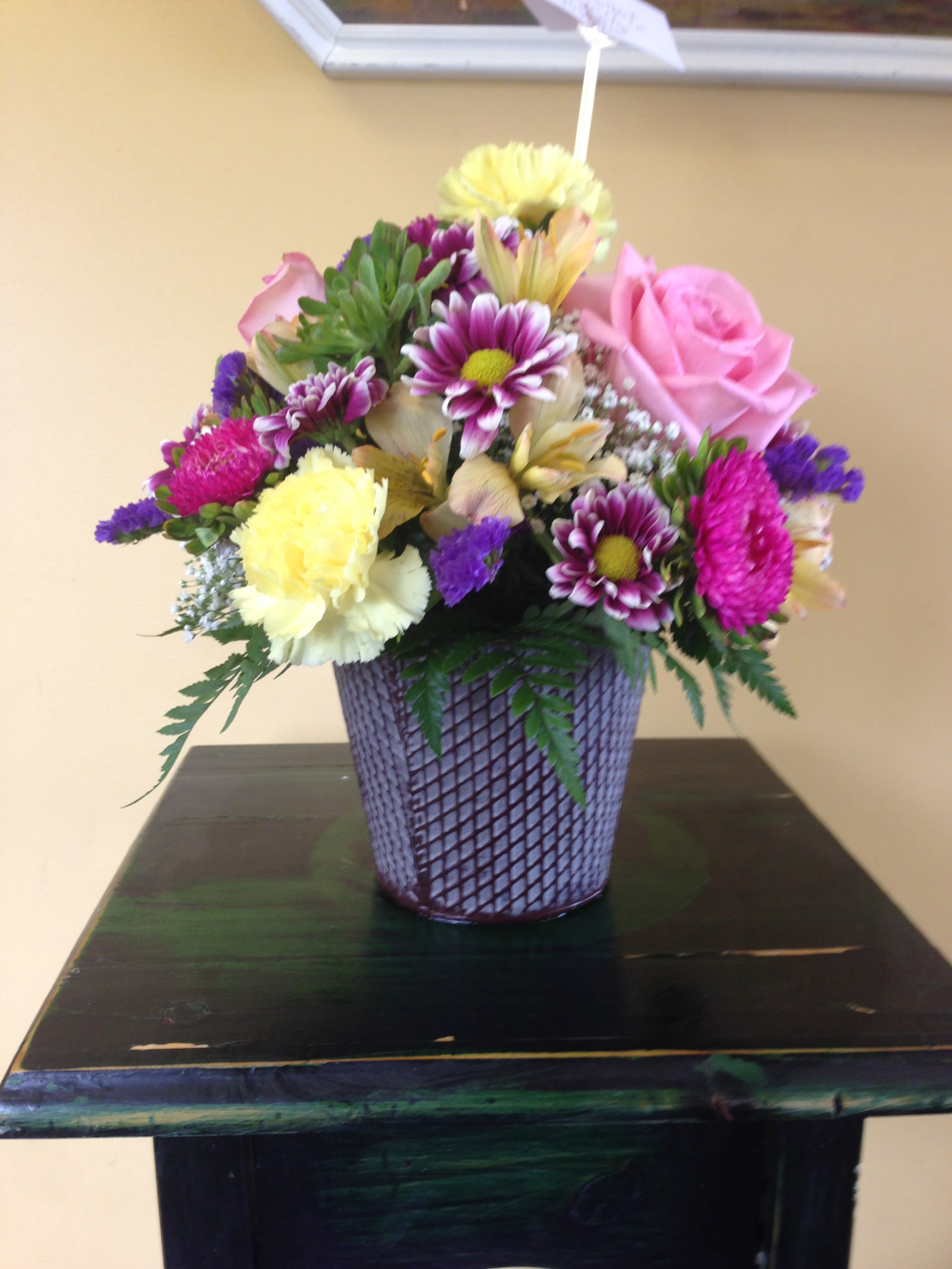 Mixed bouquet in a purple woven vase with pink and yellow blooms