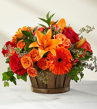 Orange and red flower arrangement in a wooden basket
