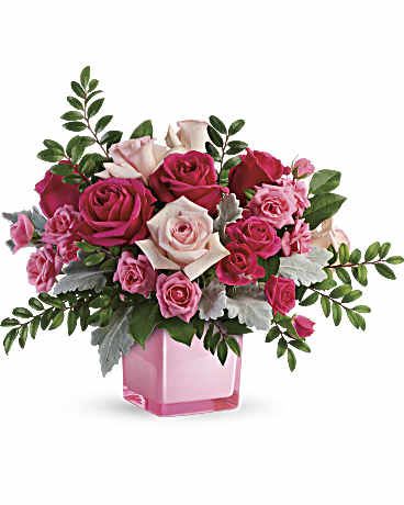 Pink and white roses arranged in a pink glass vase