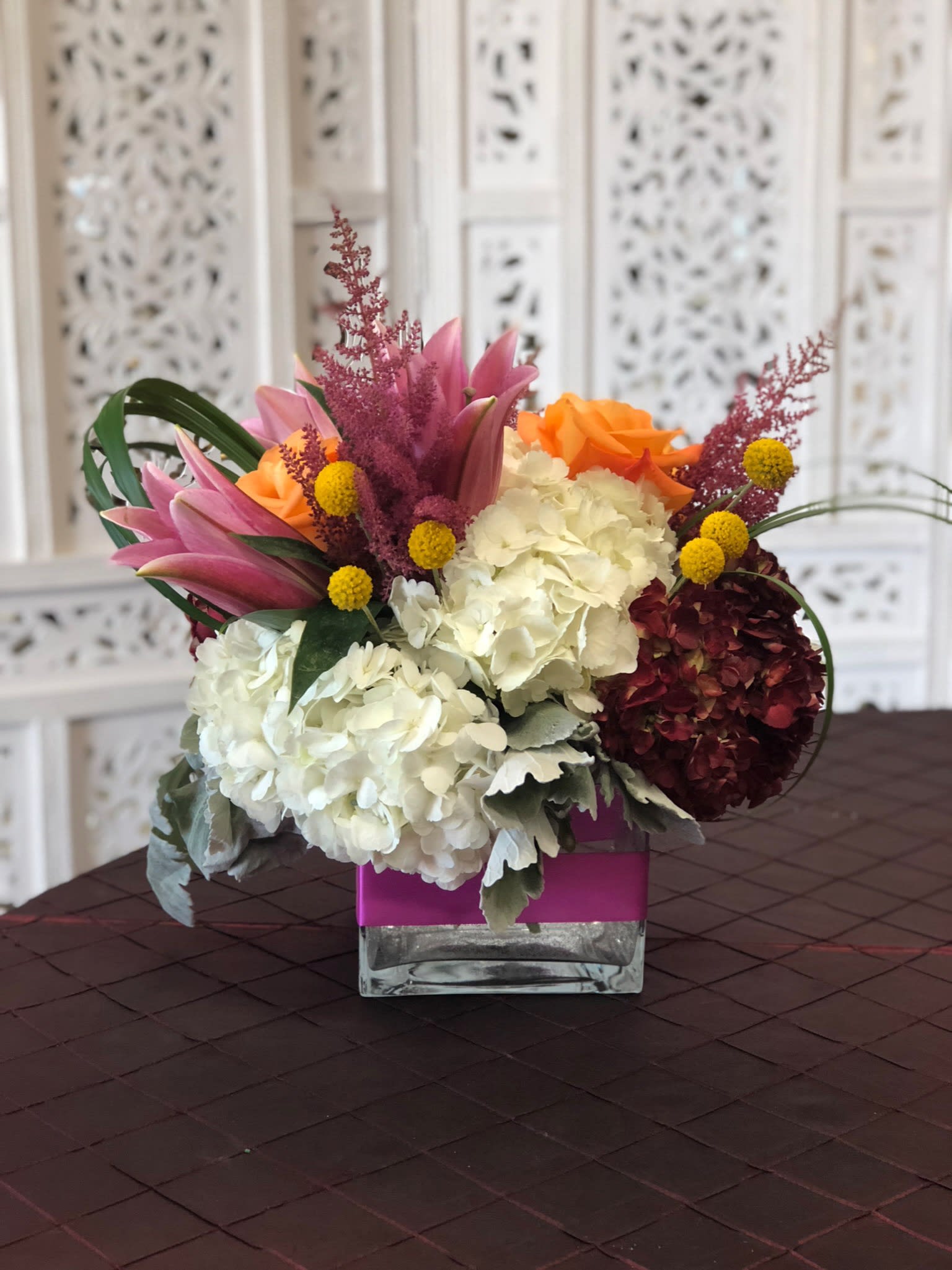 Mixed bouquet with hydrangeas, roses, and lilies in a square glass vase