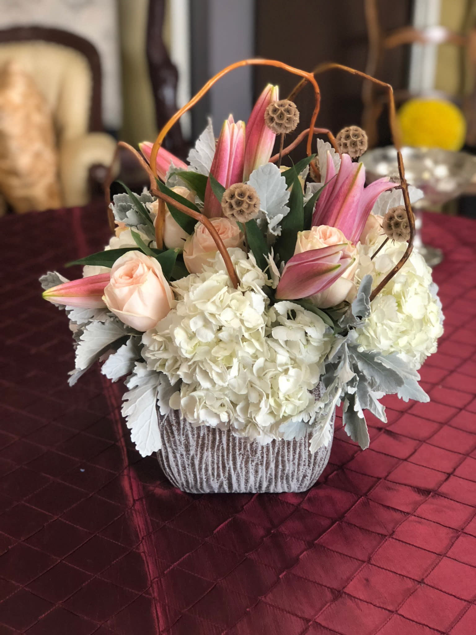 Pink lilies and pale roses arranged with white hydrangeas in a basket