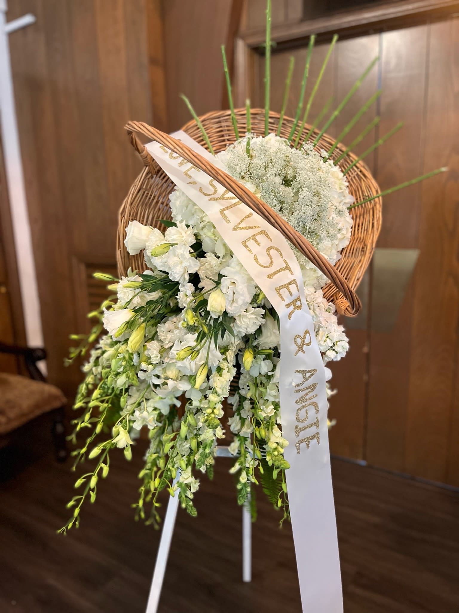 White floral standing spray with a wicker heart and ribbon