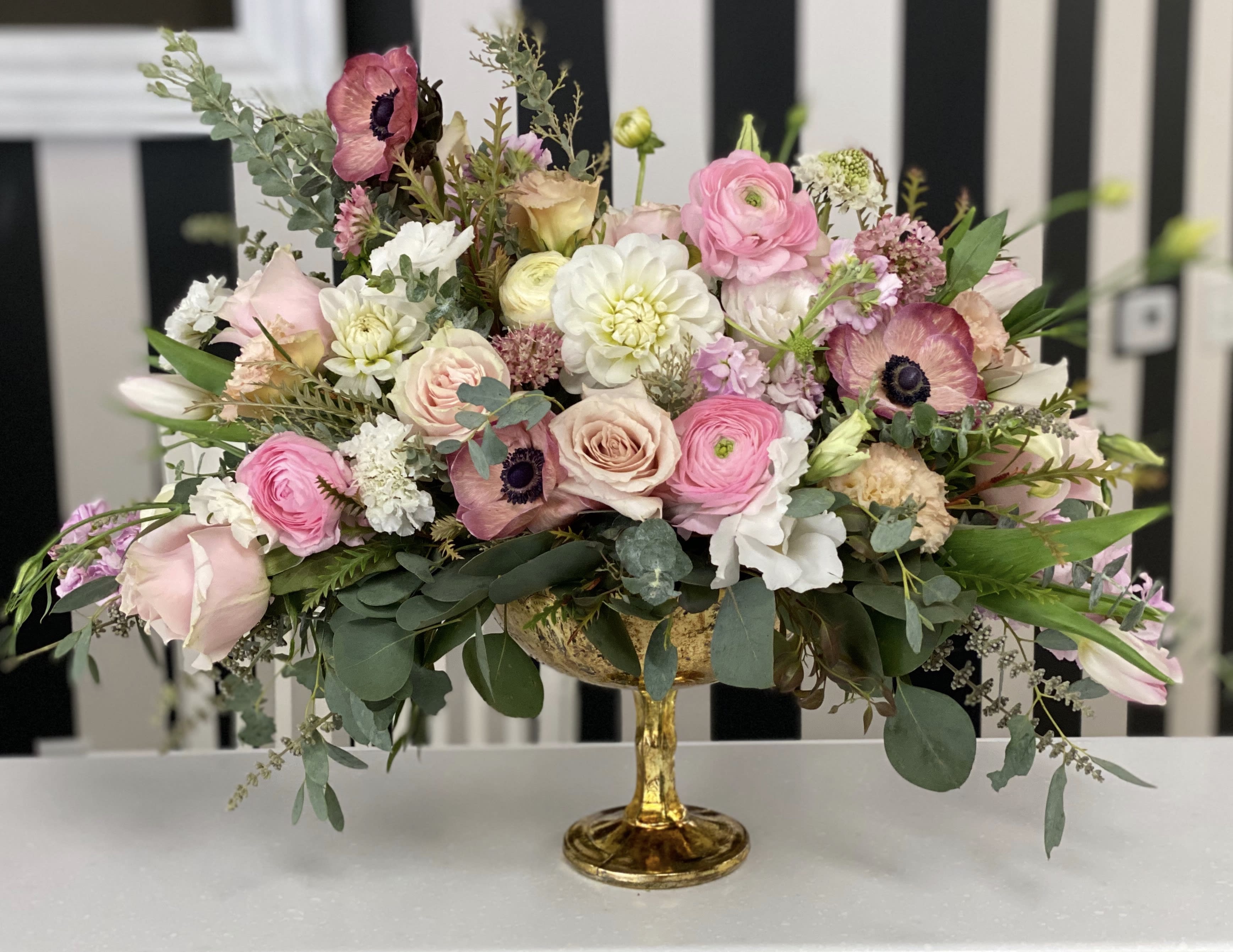 Pink and white mixed flower arrangement in a gold pedestal vase