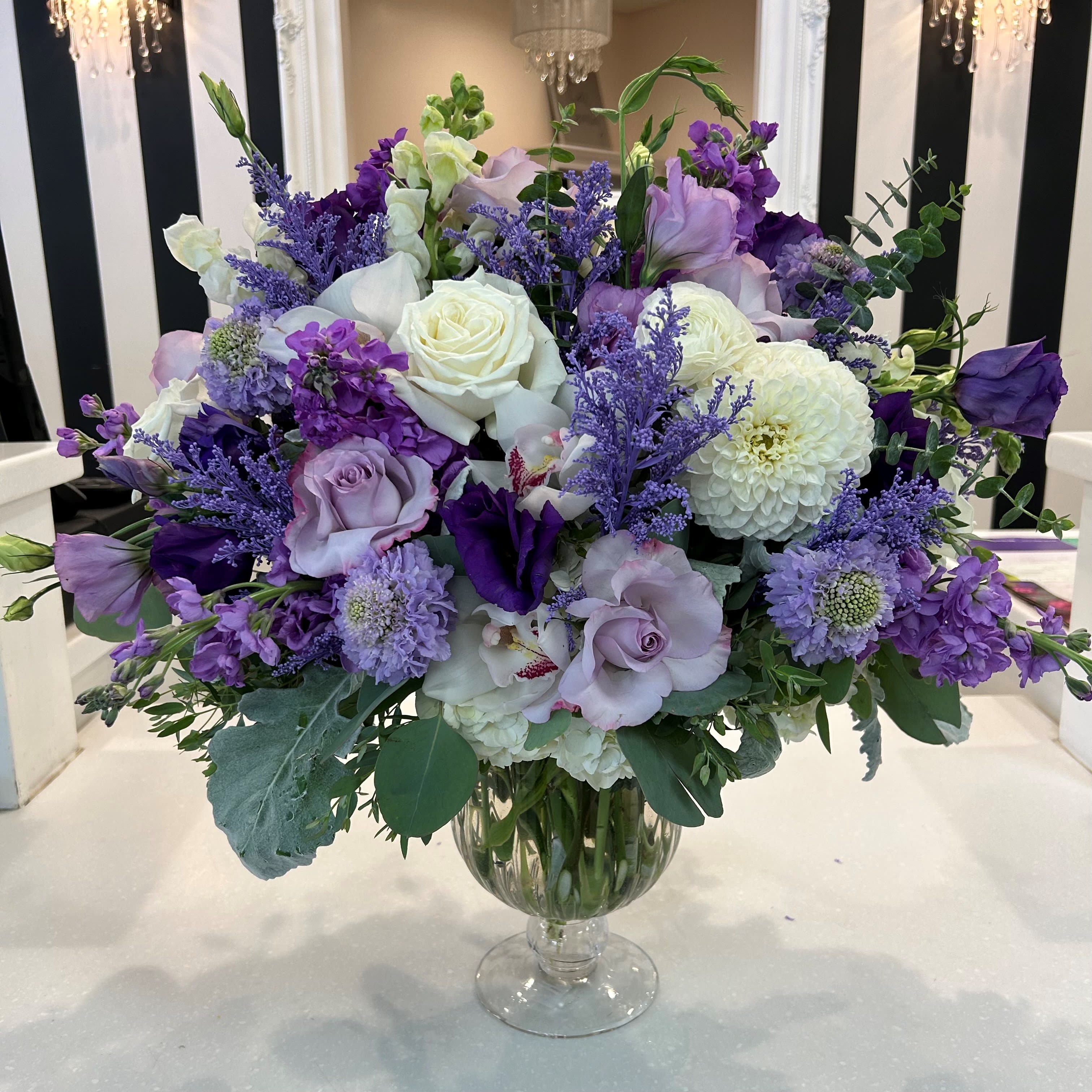 Purple and white floral arrangement in a clear glass vase