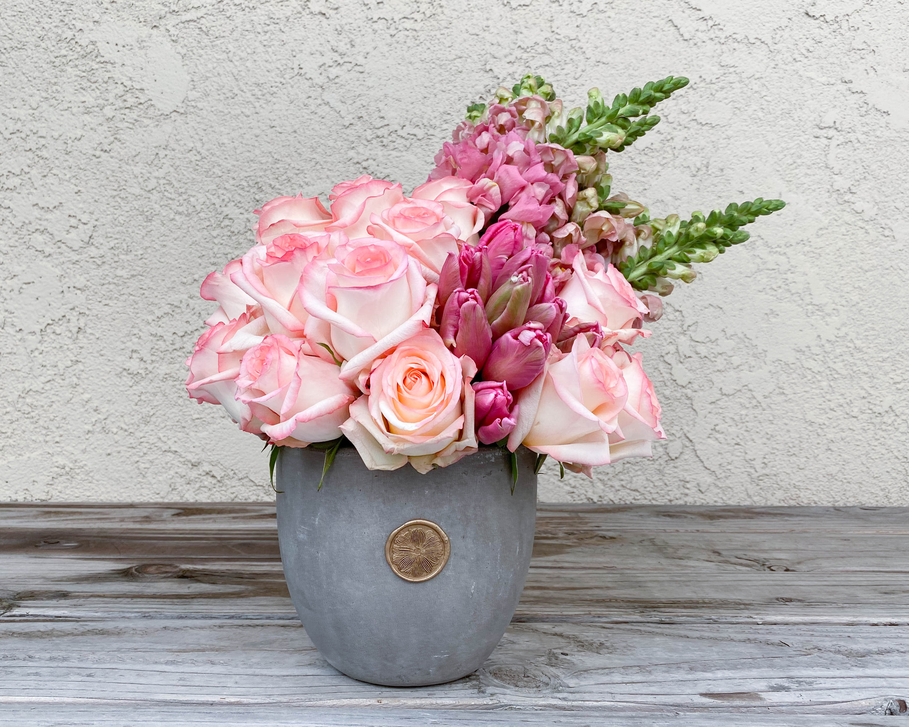 Pink roses and snapdragons arranged in a gray vase