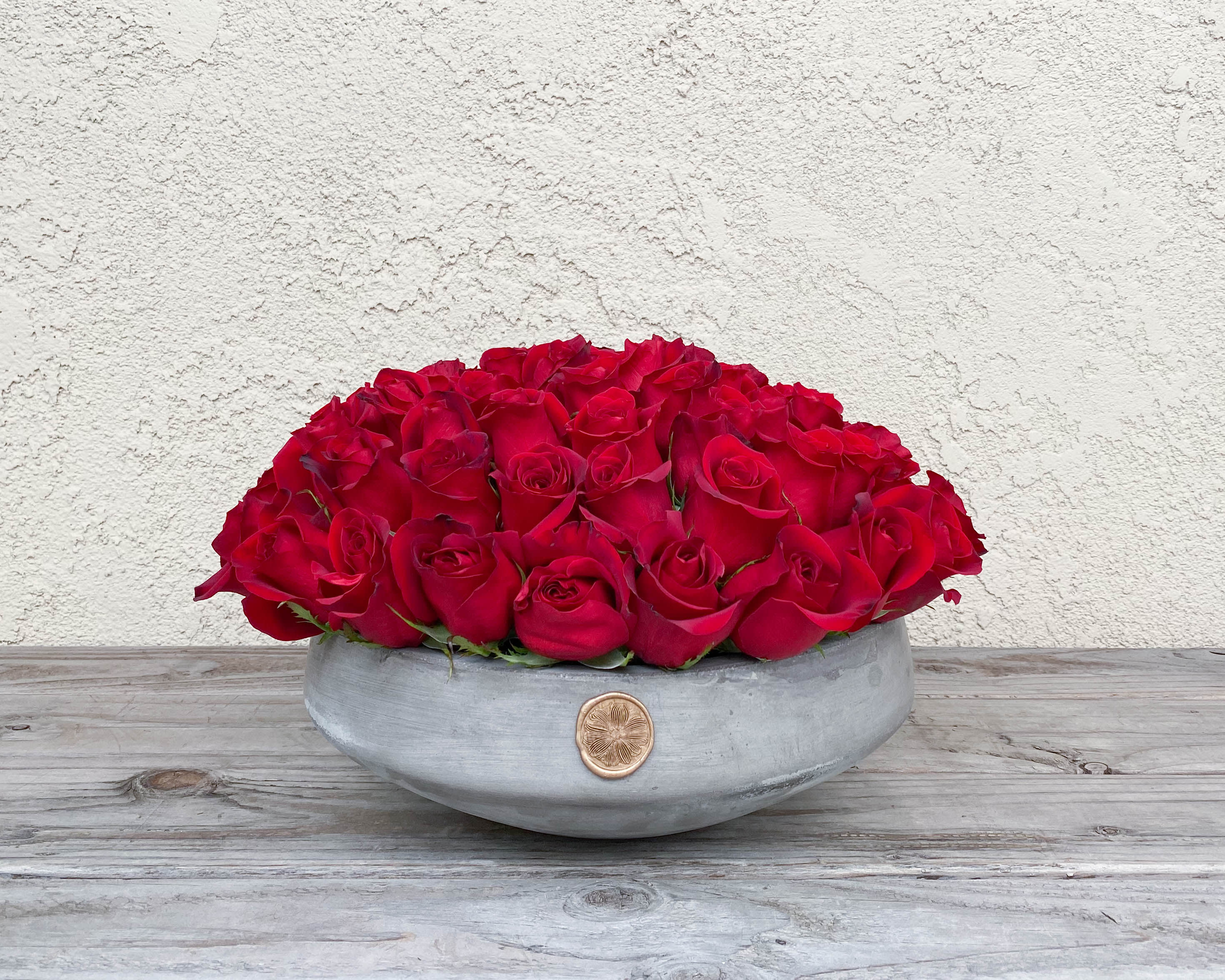 Low arrangement of red roses in a gray bowl vase