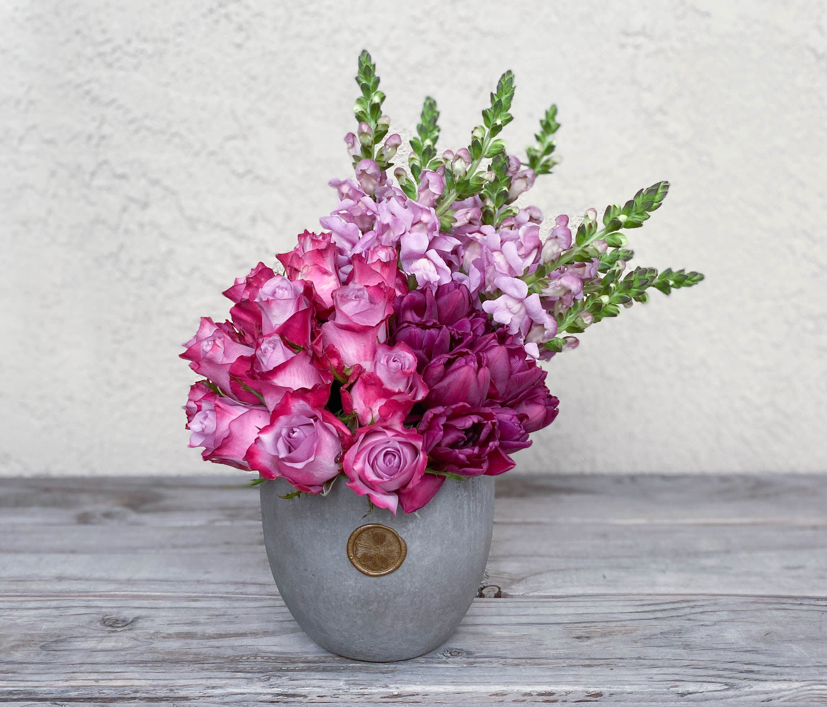 Pink and purple flowers arranged in a gray vase