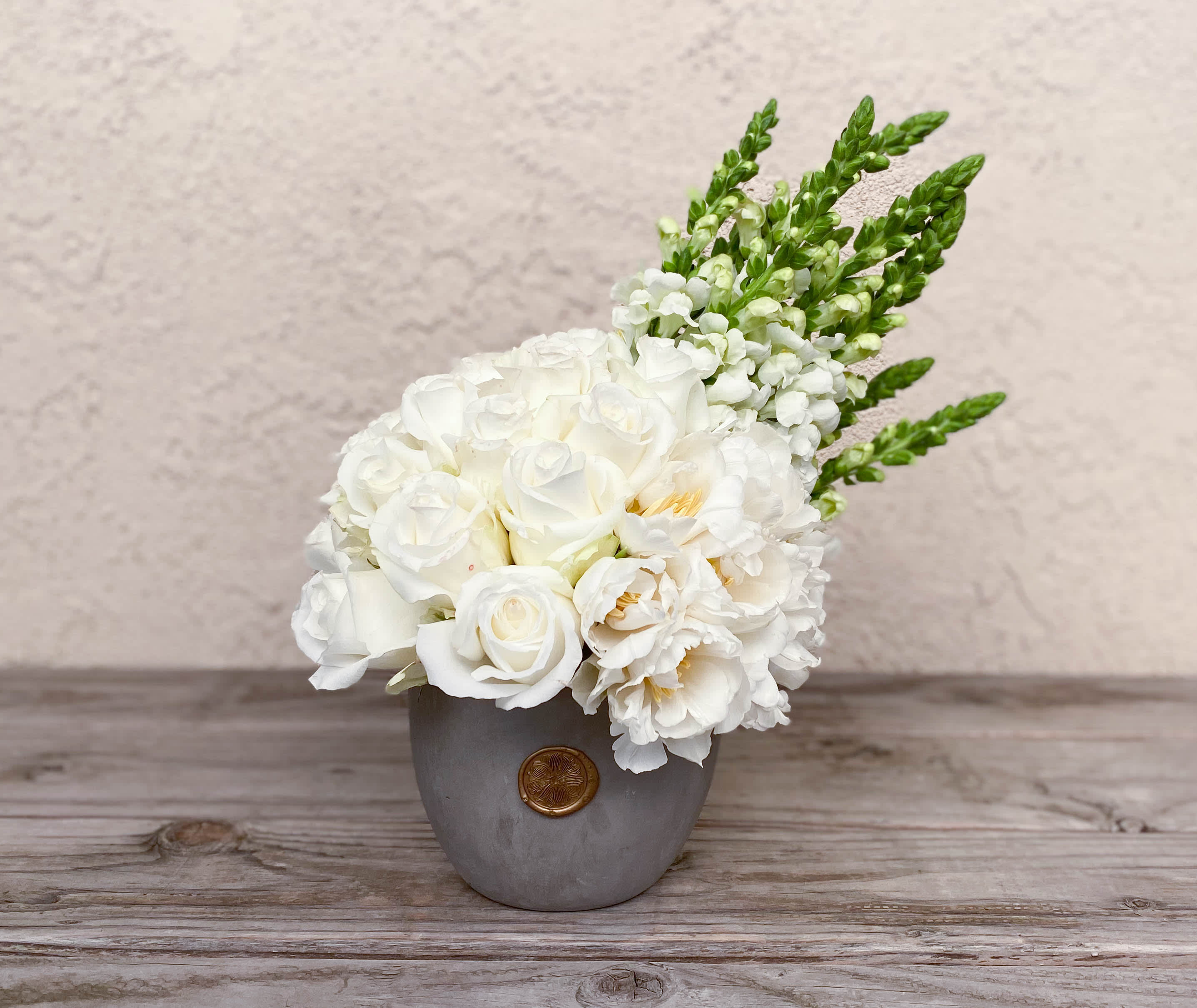 White floral arrangement in a gray vase with green spikes