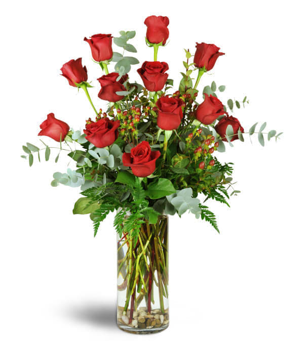 Tall arrangement of red roses in a clear glass vase with stones at the bottom