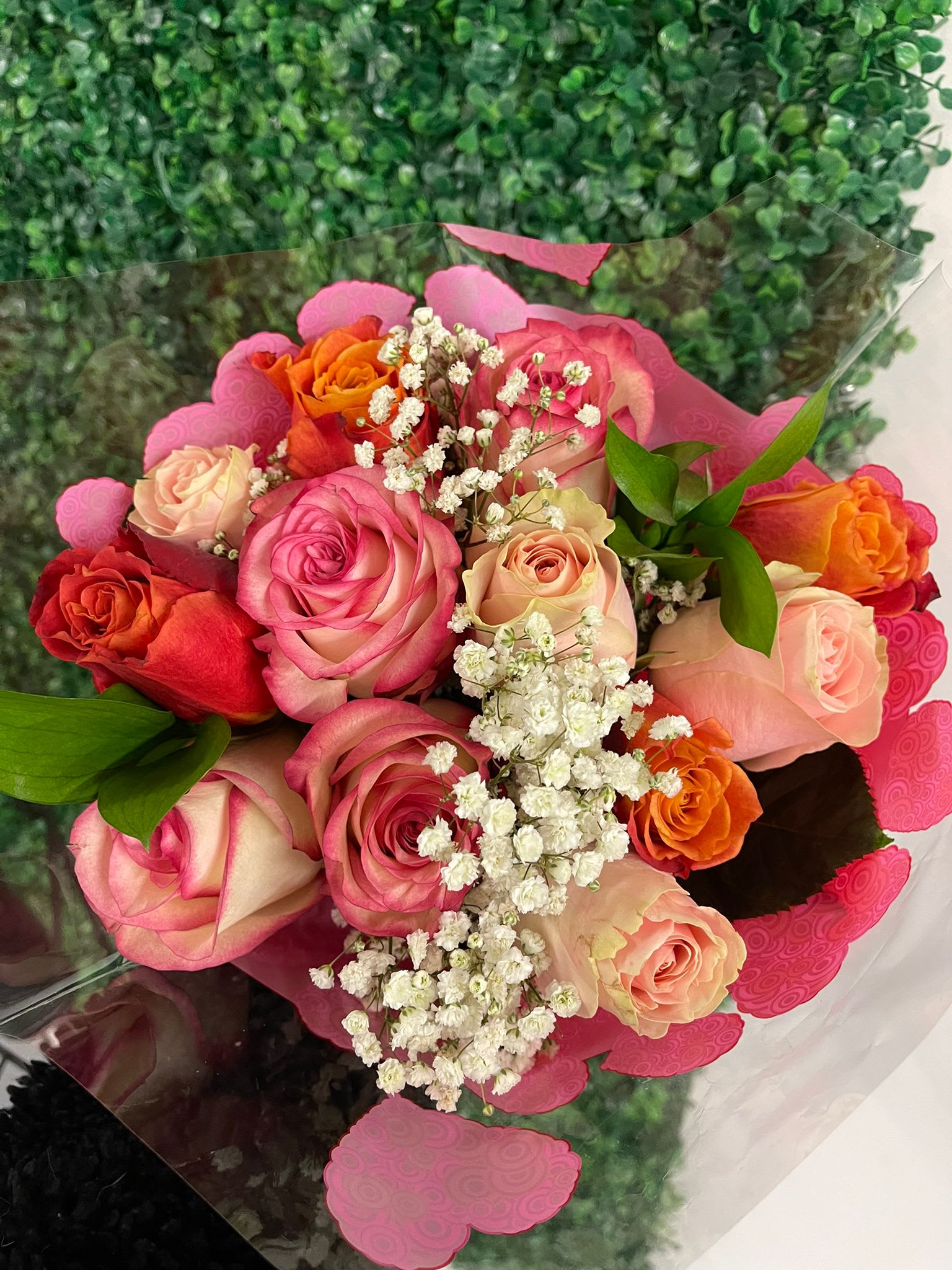 Bouquet of pink, peach, and orange roses with white baby's breath