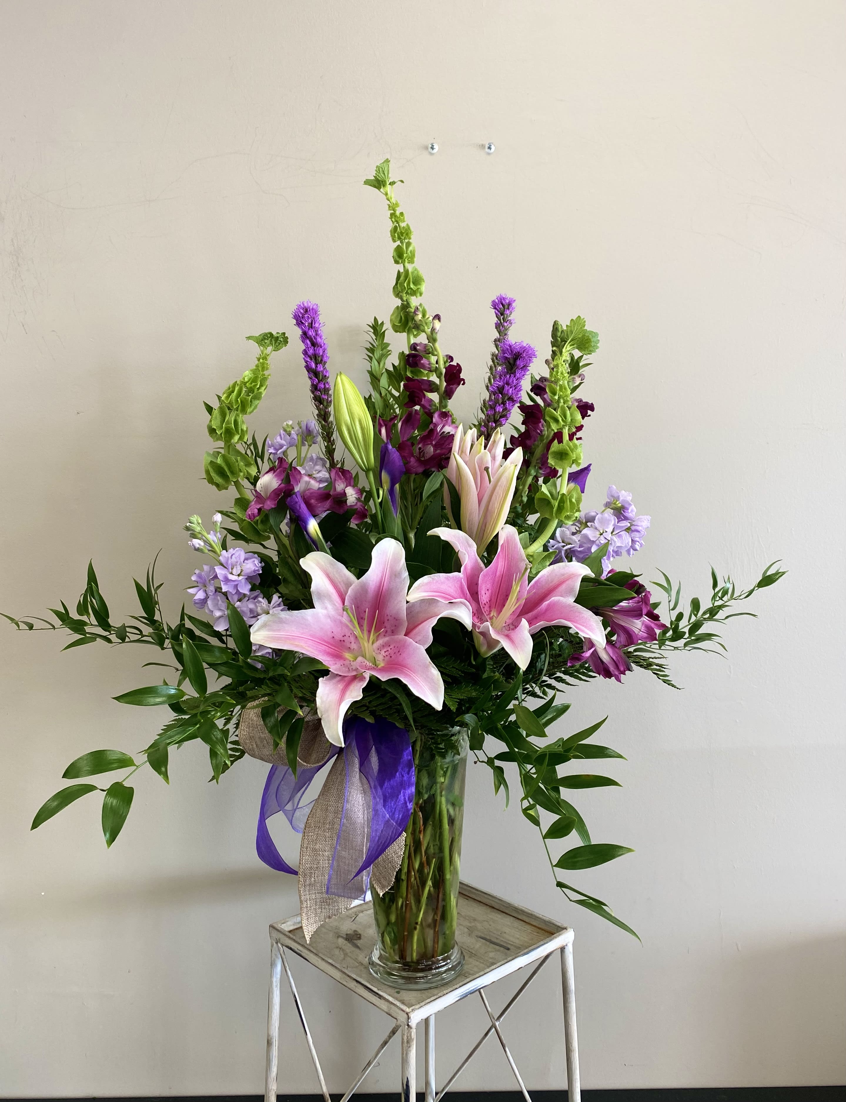 Tall bouquet of pink lilies and purple flowers in a glass vase