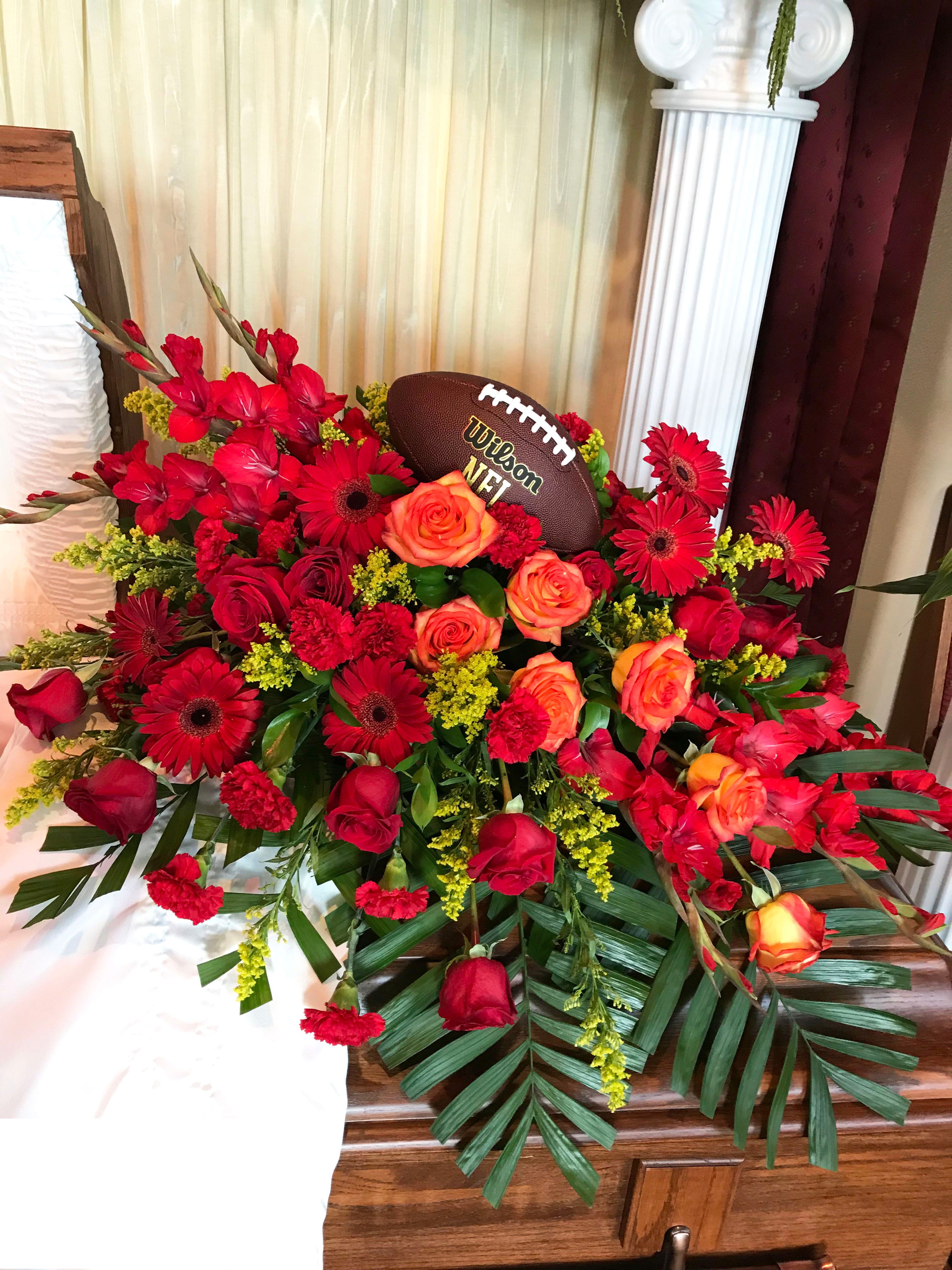 Red and orange floral arrangement with a football centerpiece