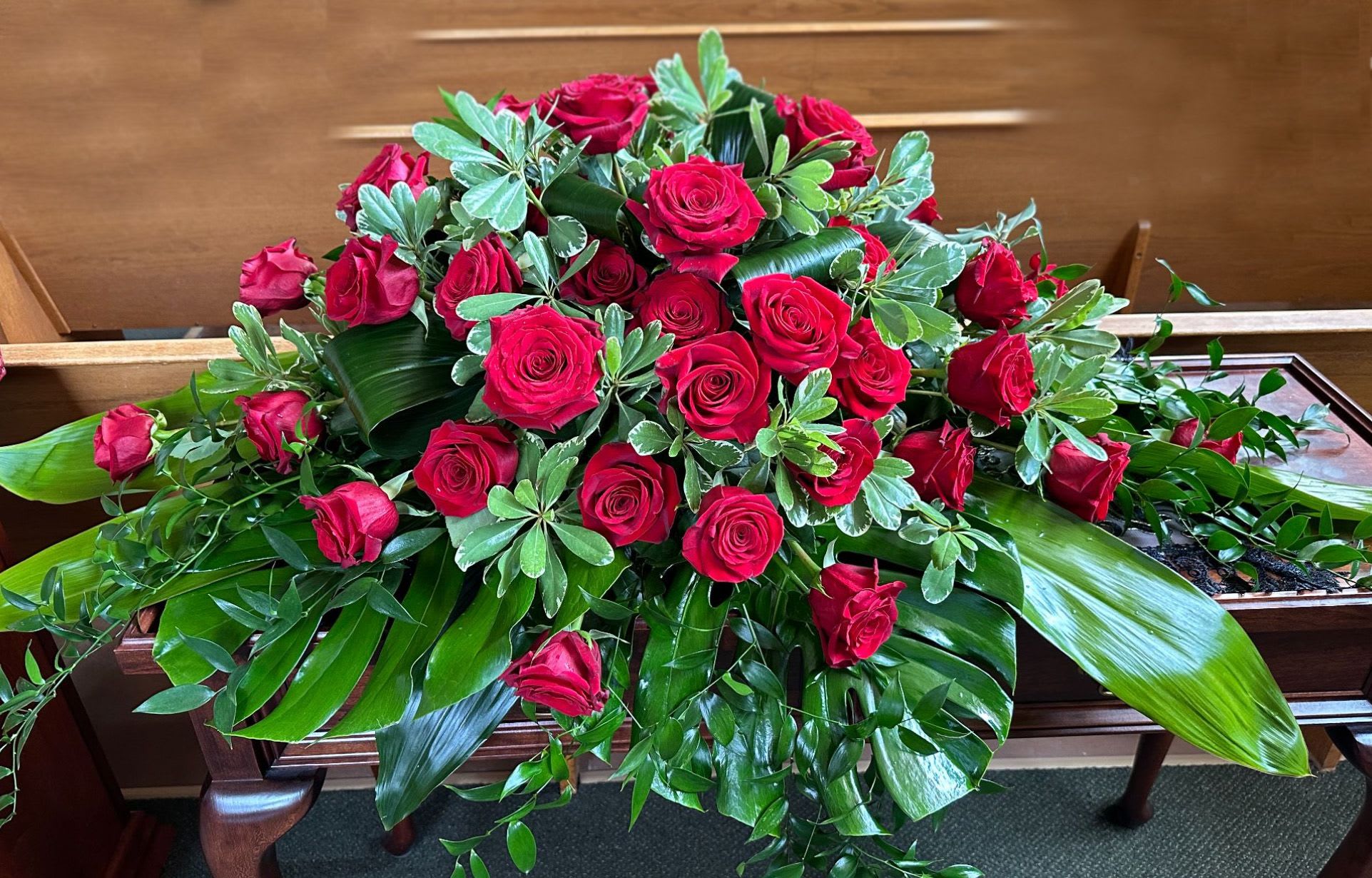 Large arrangement of red roses with broad green foliage