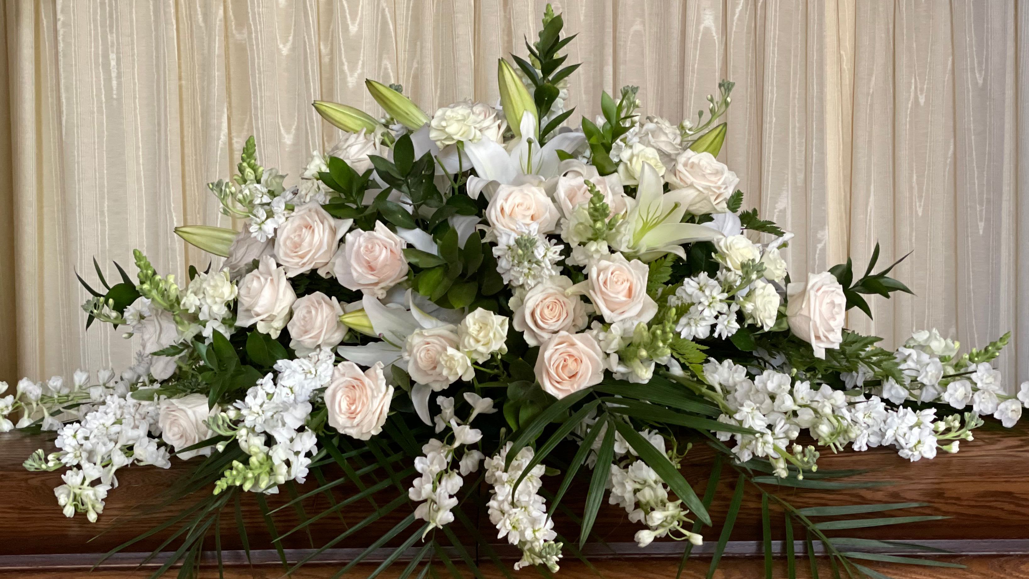 Large white and blush floral casket spray with lilies and roses