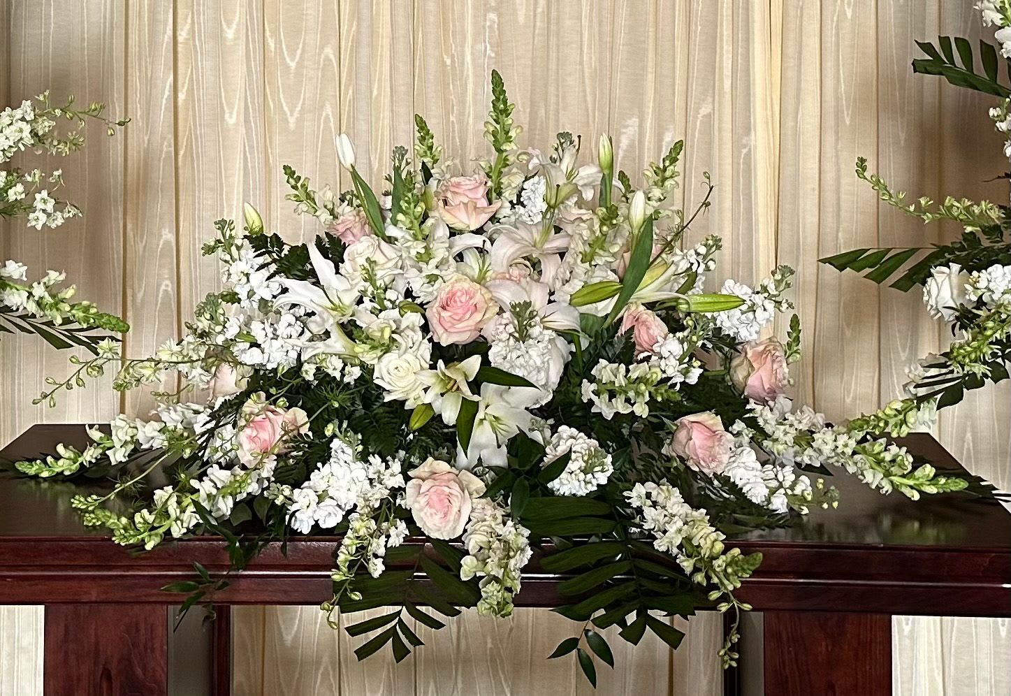 Large white and blush floral casket spray with lilies and roses