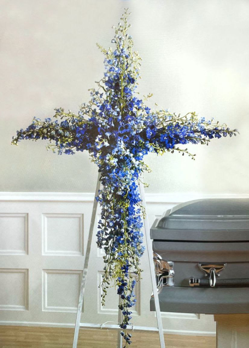 Blue floral cross on a stand beside a casket