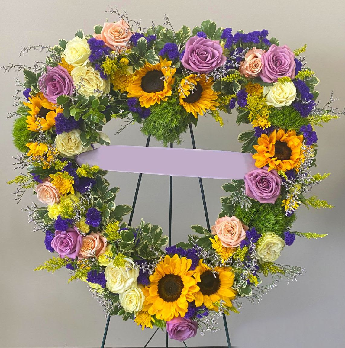 Heart-shaped floral wreath with sunflowers and roses on an easel