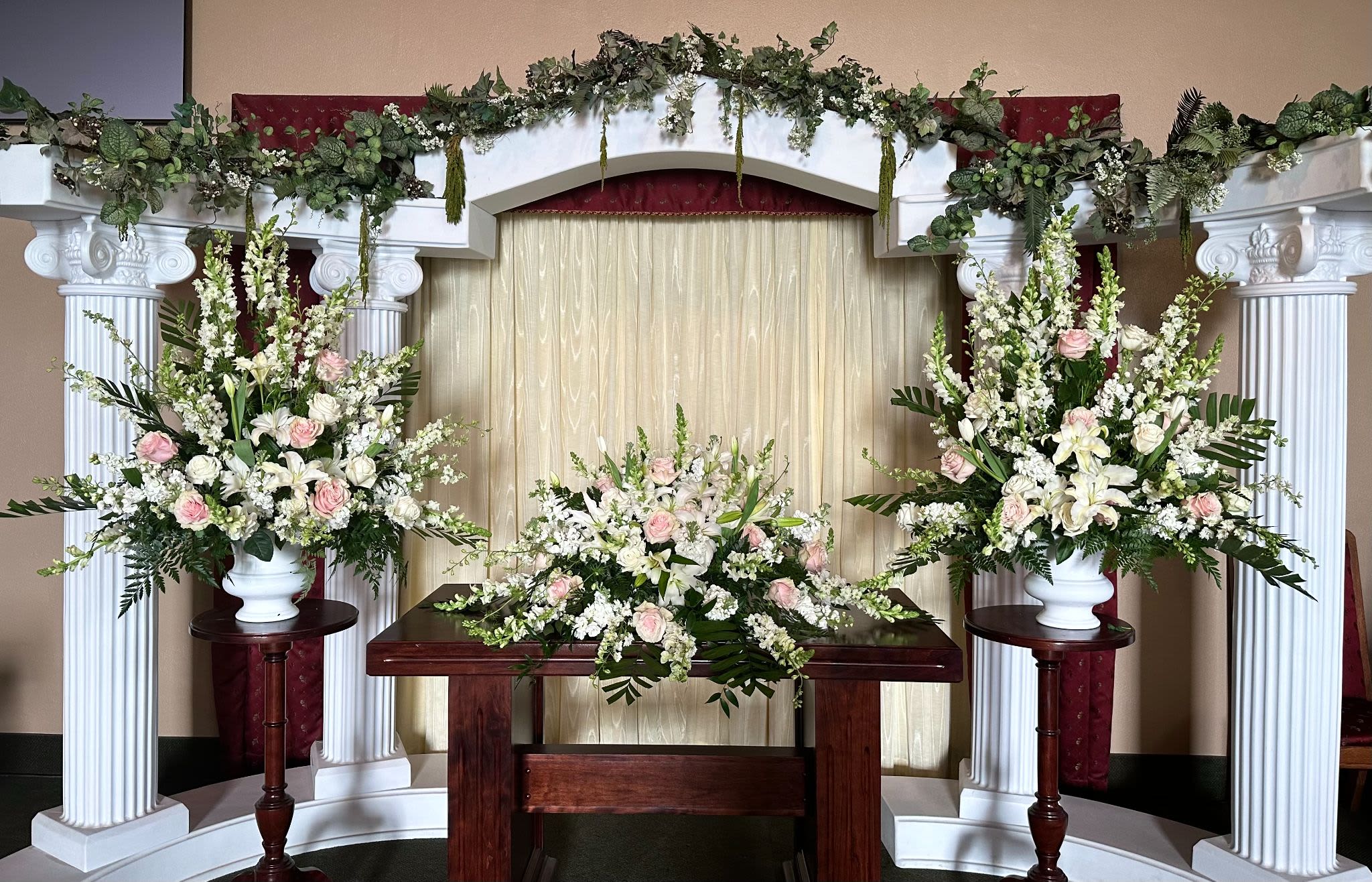Wedding altar with white and blush floral arrangements on columns and table
